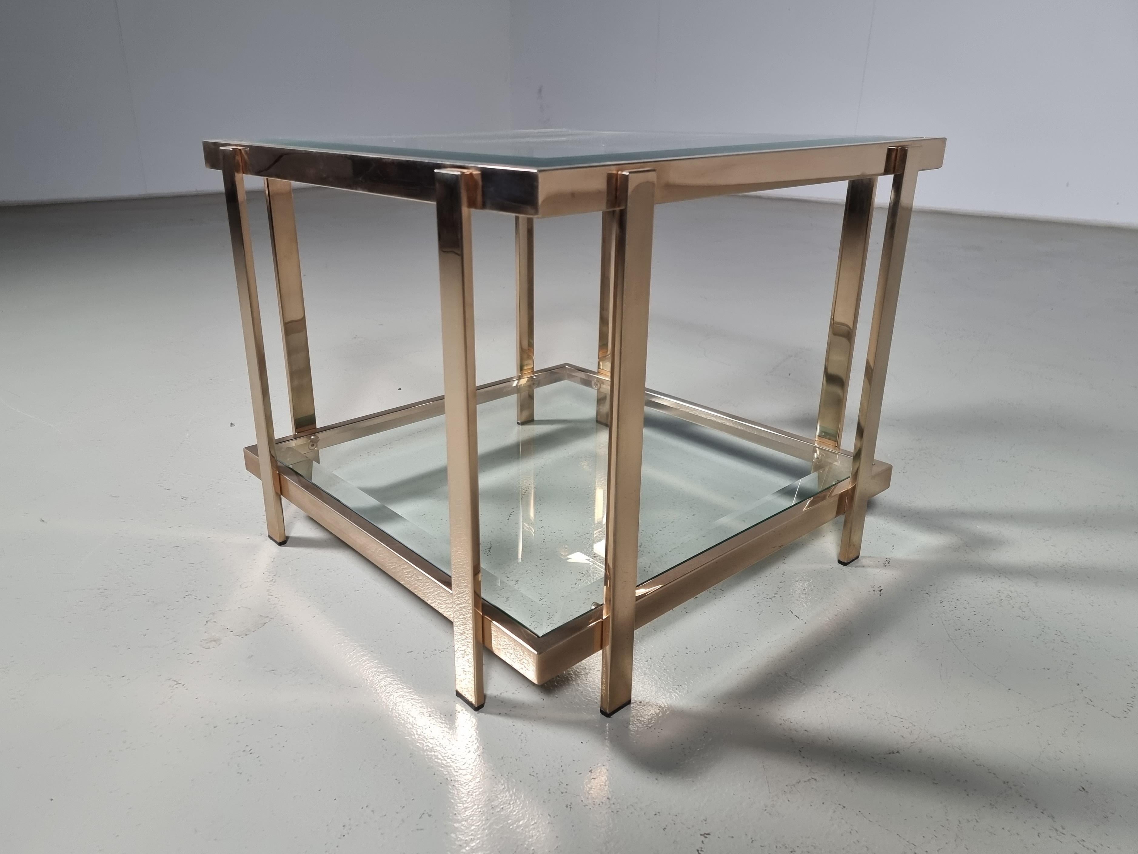 This beautiful side table was made in the early 1980s by Belgian Belgo Chrome.
The table has a metal frame that is gold plated with a thin layer of 23-carat gold. 

The table features two faceted glass plates, The legs are equipped with plastic