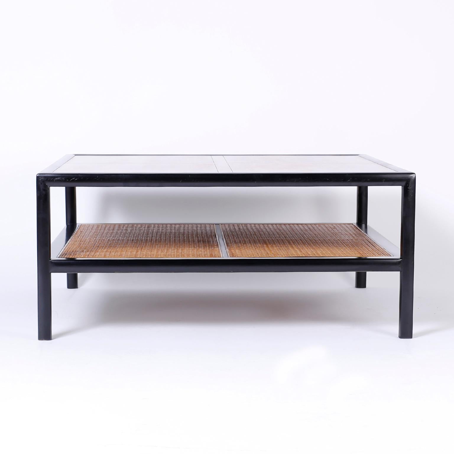 Chic Baker, two-tiered coffee or cocktail table with a sleek black lacquer frame, walnut top, and a caned lower plateau that adds a British Colonial influence.