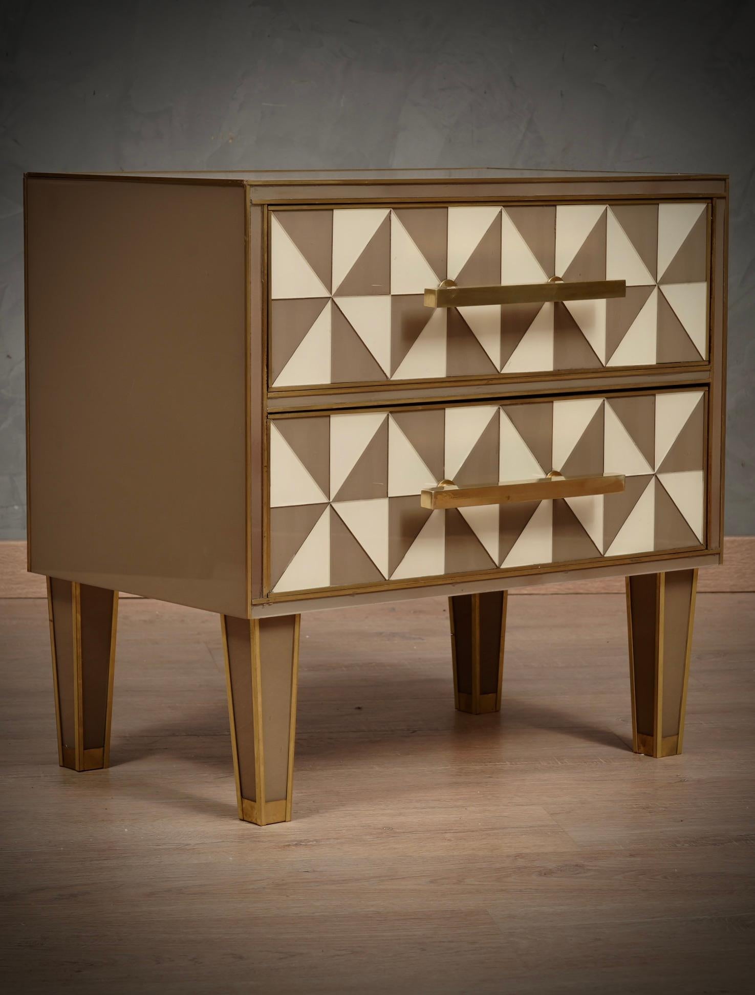 Classic design for a pair of night tables all in dove gray and white colored glass and brass. Square and linear as in the style of that design.

The bedside tables have a wooden structure, above they have been covered in dove-gray and cream-colored