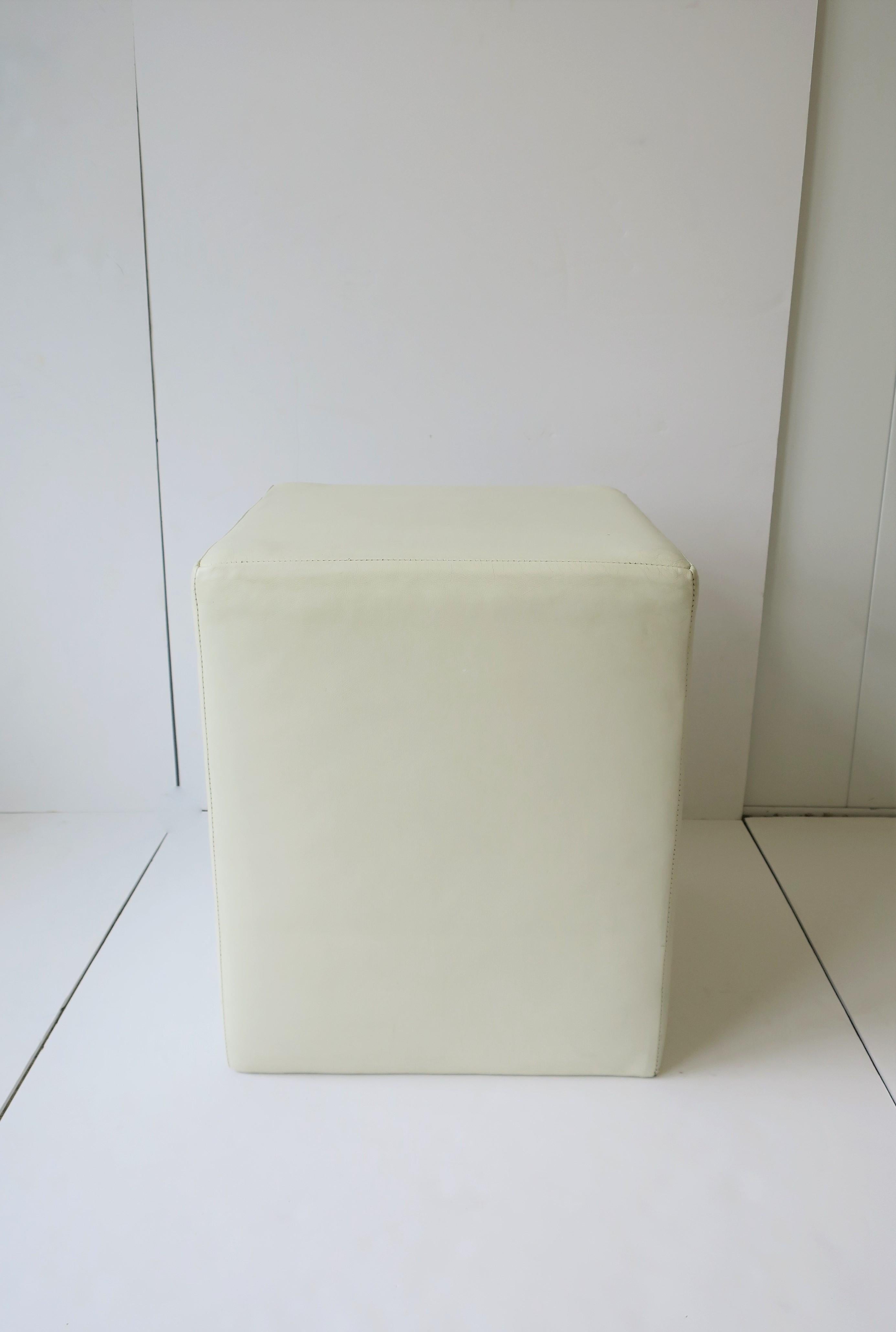 A Modern style white leather stool or end table. Piece makes a comfortable, moveable stool/seat, or even as a side or end table with is a firm environment on top (e.g. a book) as demonstrated in images. Dimensions: 15.5
