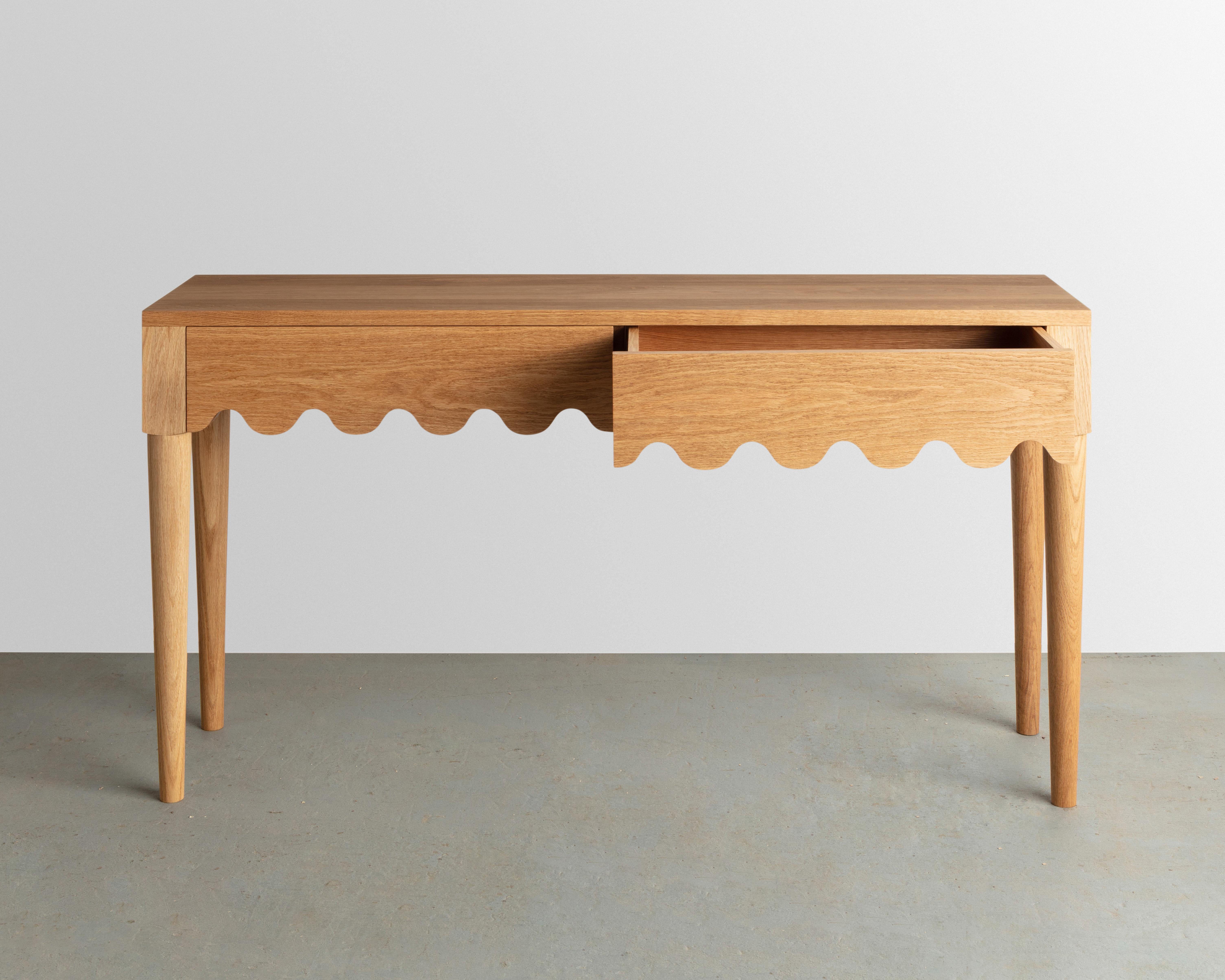 Designed and built in the studio this entryway table features a playful detail that continues along its double drawer faces and seamlessly wraps around its form. 

Made from solid oak-inspired by the French Mid-century designer Jean Royère.
