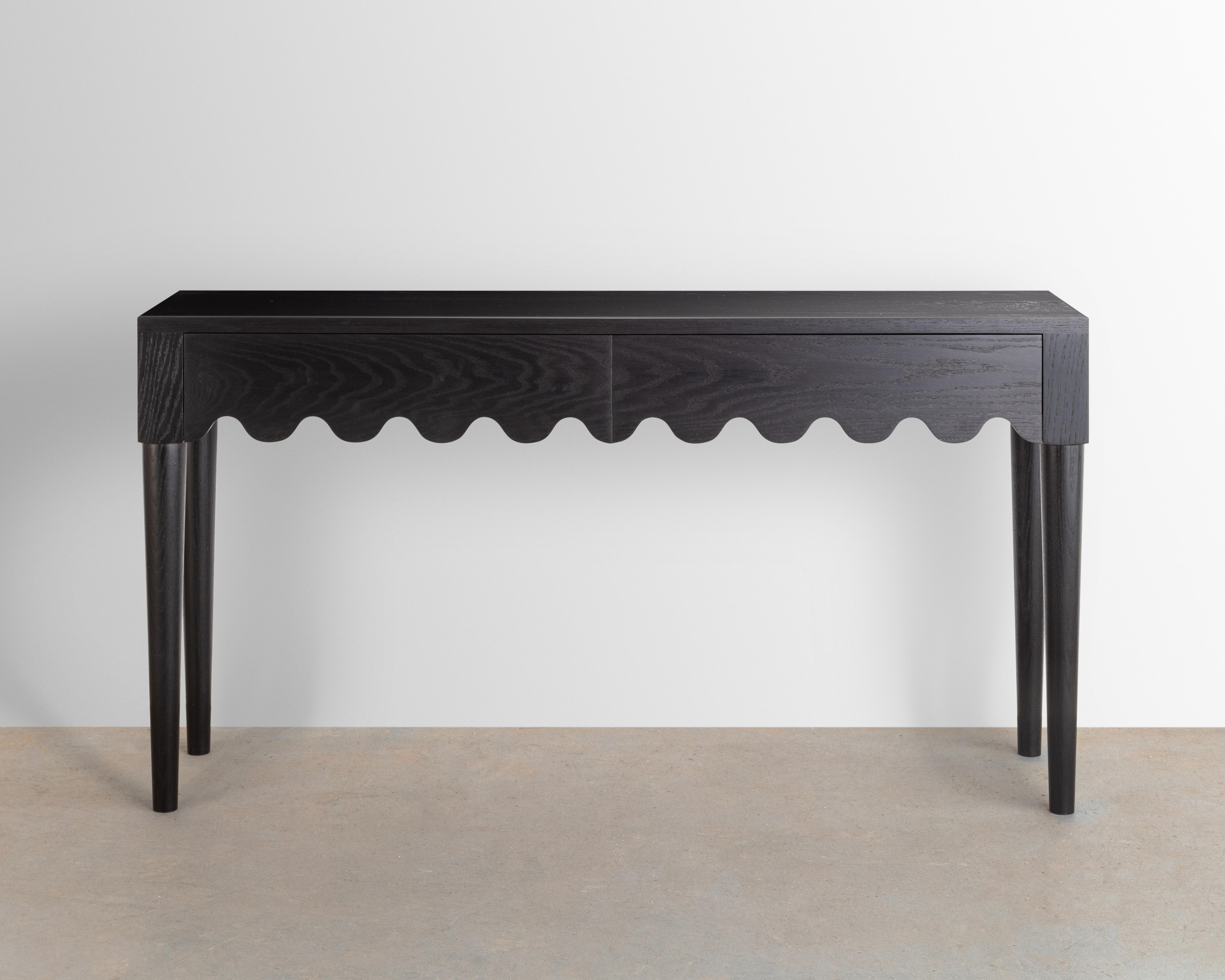 Designed and built in the studio this entryway table features a playful detail that continues along its double drawer faces and seamlessly wraps around its form. 

Made from solid ebonized oak- inspired by the French mid-century designer Jean