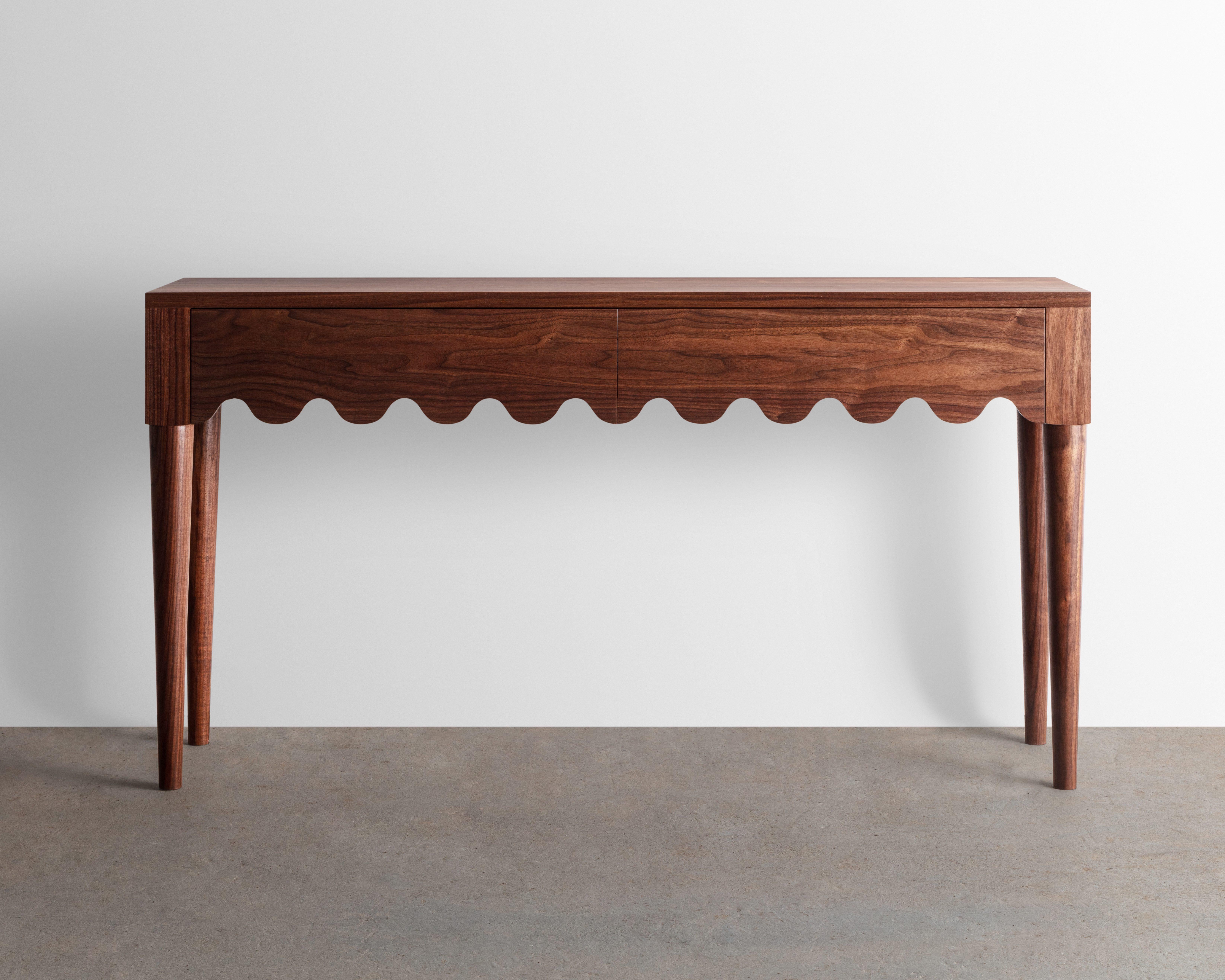 Designed and built in the studio this entryway table features a playful detail that continues along its double drawer faces and seamlessly wraps around its form. 

Made from solid Walnut -inspired by the French mid-century designer Jean Royère.
 