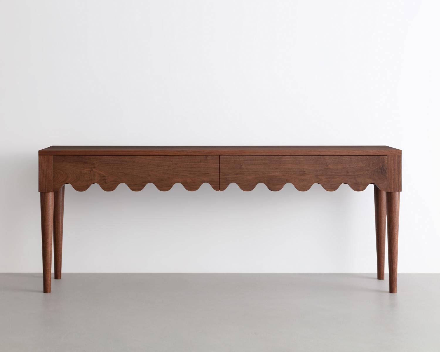 Designed and built in the studio this entryway table features a playful detail that continues along its double drawer faces and seamlessly wraps around its form. Hand turned solid Walnut legs complete its form.

Made from solid Walnut -inspired by