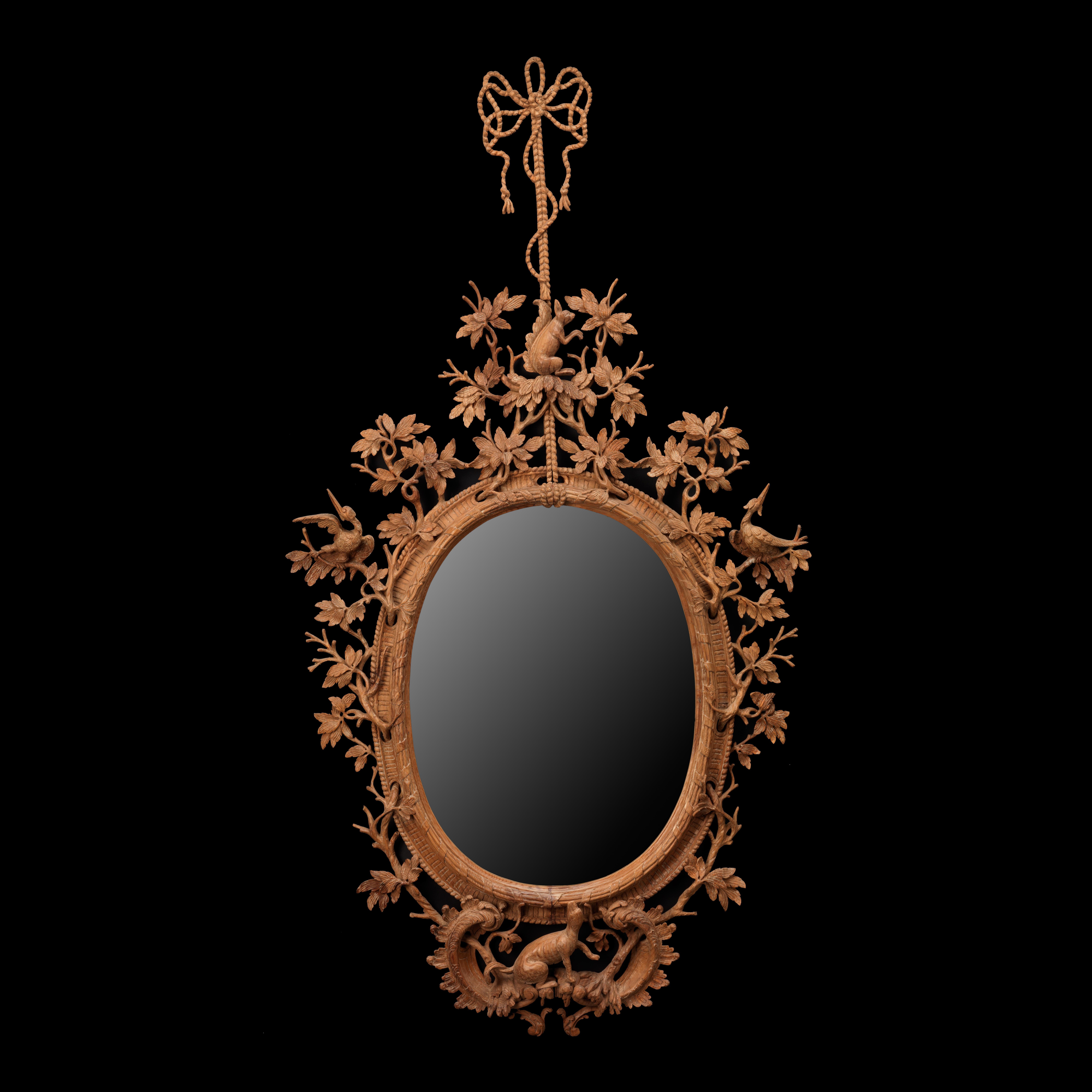 A fine naturalistically carved oval mirror with bird, branch and stylized animal decoration in the manner of Thomas Johnson. An exceptionally fine mirror carved in period old pine with an 18th century wax finish.

We are currently working to a 30-36