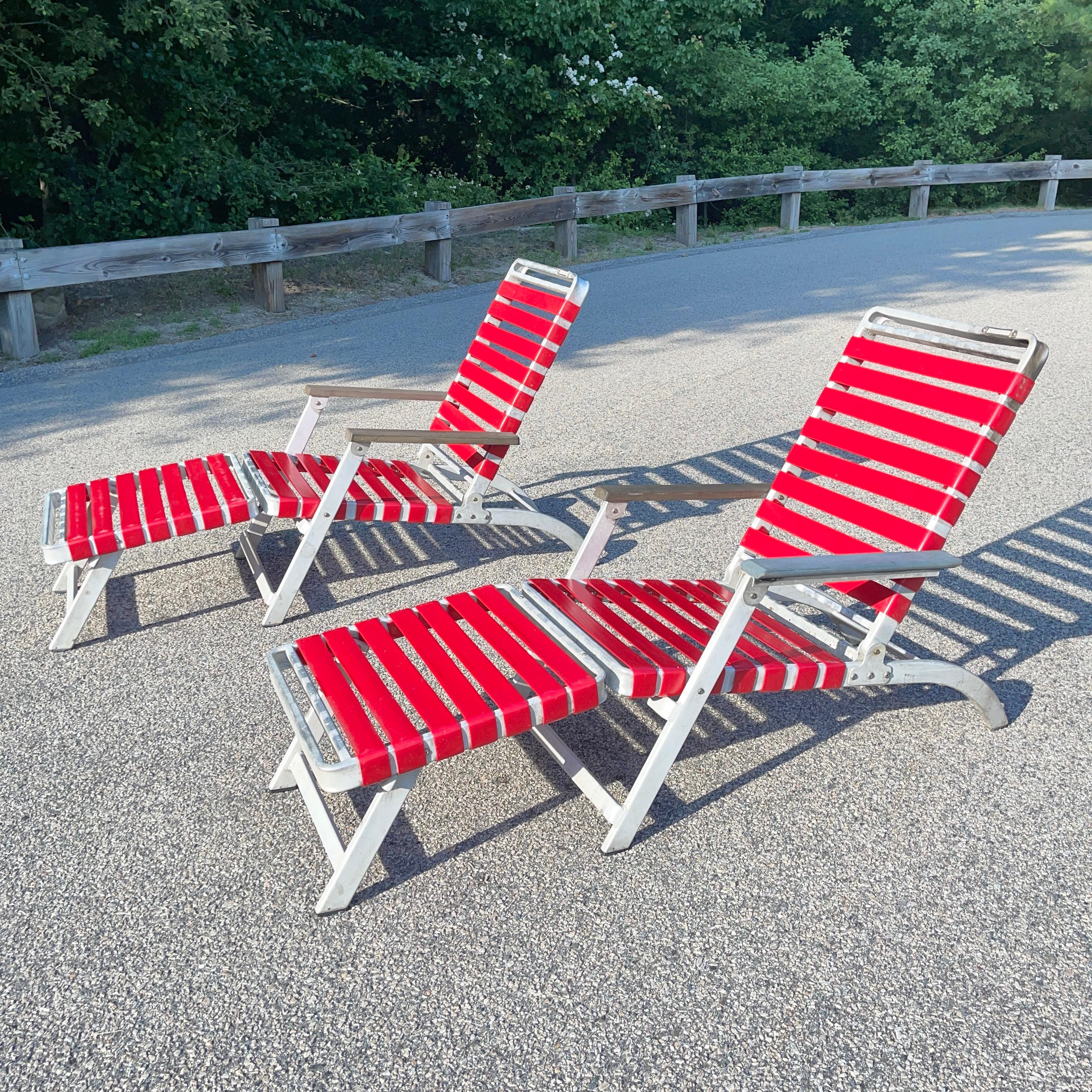 These two folding aluminum lounge chairs were made for the SS United States ocean liner and produced by the Troy Sunshade Company in 1952. 
Note the slot for name tag for passengers who would have reserved the chair aboard the ship.
Red