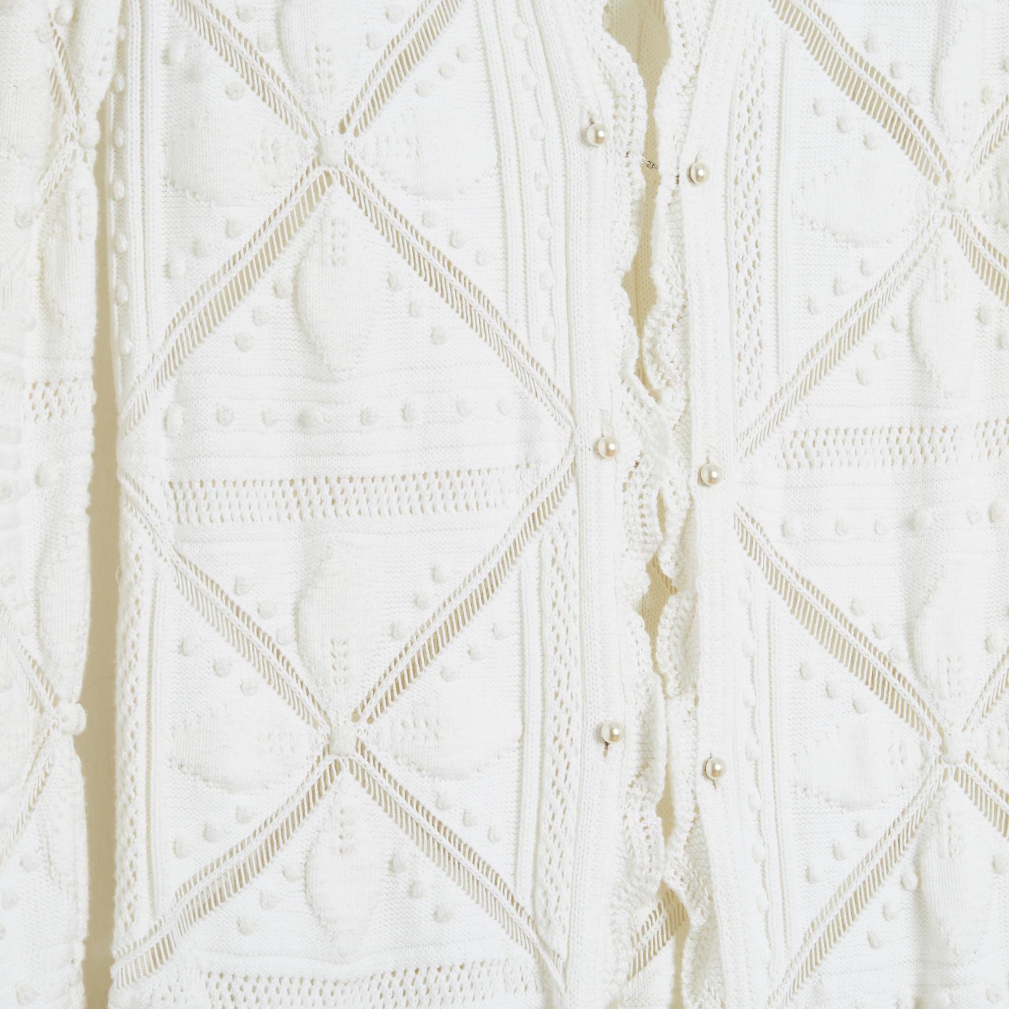 Chanel long jacket SS 2004 collection cardigan en coton blanc tricoté avec des motifs géométriques et des bords volantés, fermé sur le devant par 3 barrettes ornées de perles fantaisie, non doublé. Taille 38FR soit US8 : taille 40 cm, poitrine 42