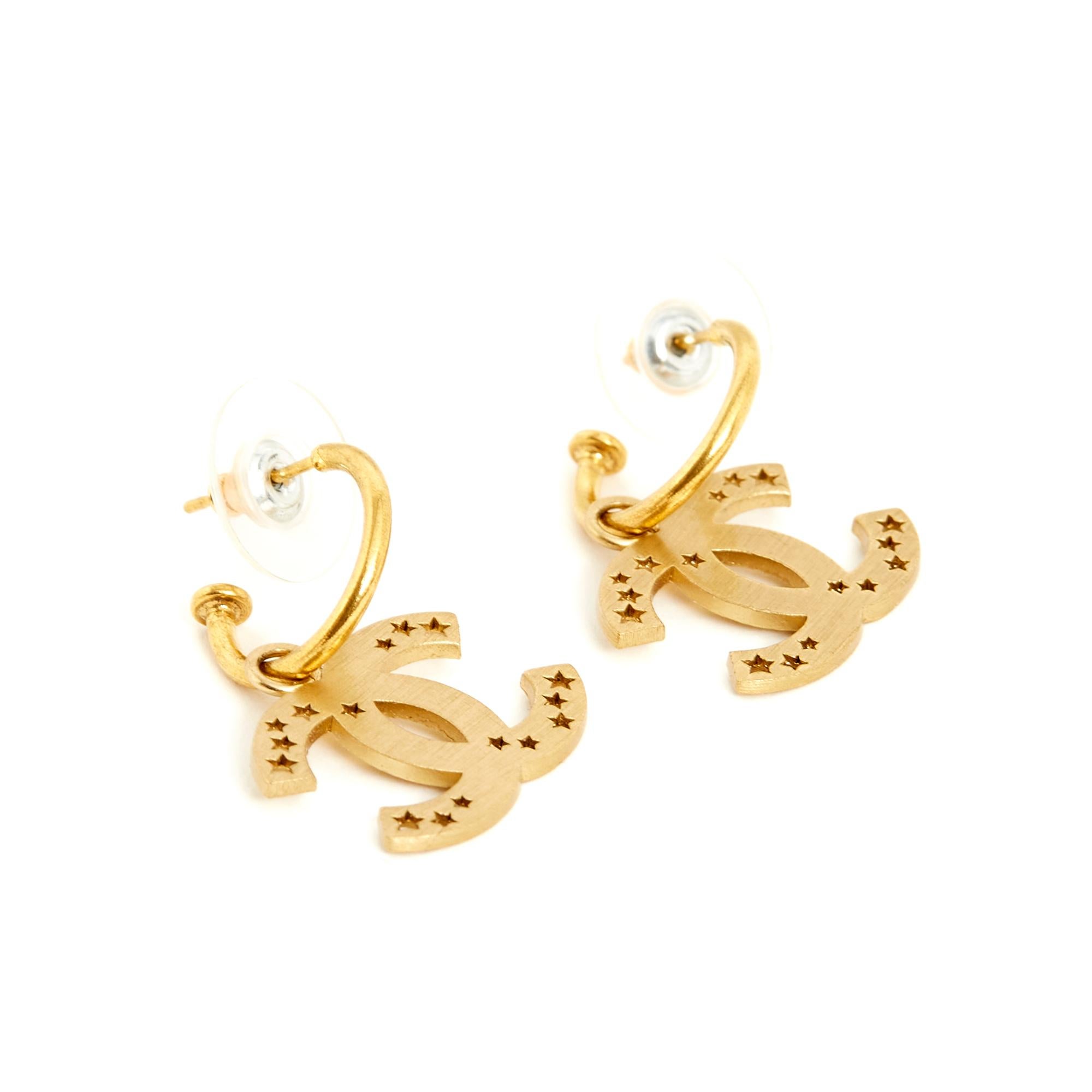 Chanel earrings in gold metal composed of a small hoop and a pendant with the motif of the CC logo in matte or brushed gold and openwork with small stars of different sizes. Diameter of the hoop 1.55 cm, dimensions of the CC 1.95 x 1.45 cm, total
