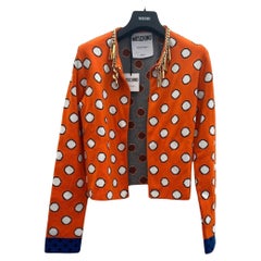 Moschino Couture SS21 - Cardigan orange avec cercles blancs et breloques avec logo de Jeremy Scott
