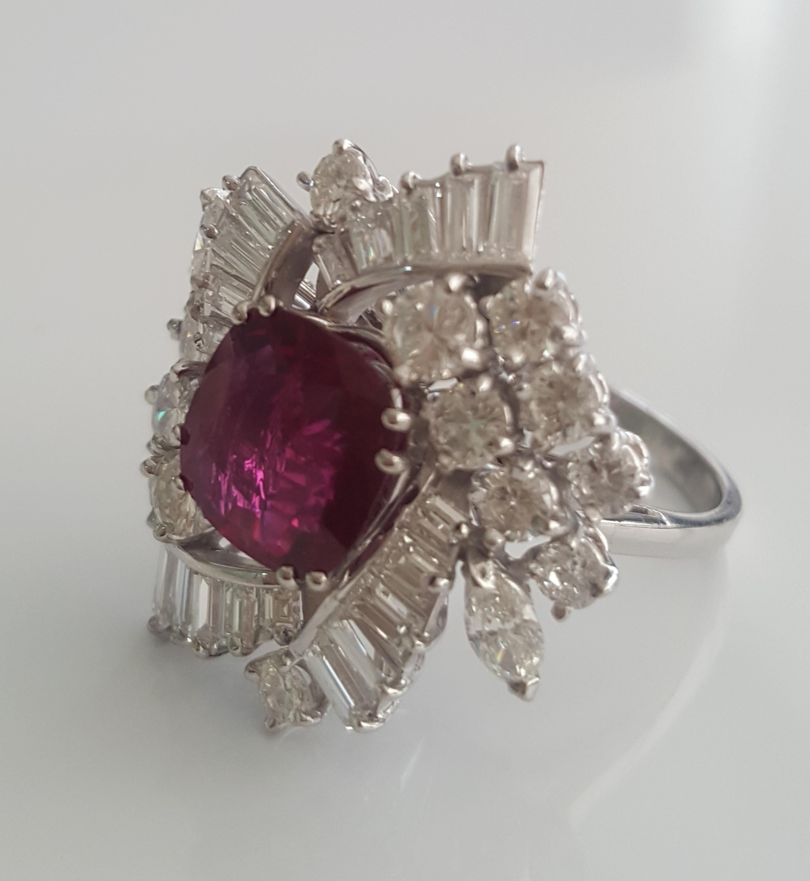 This magnificent, stunning and extraordinary ring features SSEF certified natural cushion ruby SIAM weighing 2.50 carat encircled by white baguettes and white round brilliant diamonds. The ring face measures 25mm x 21 mm. The ring size is 5 3/4 and