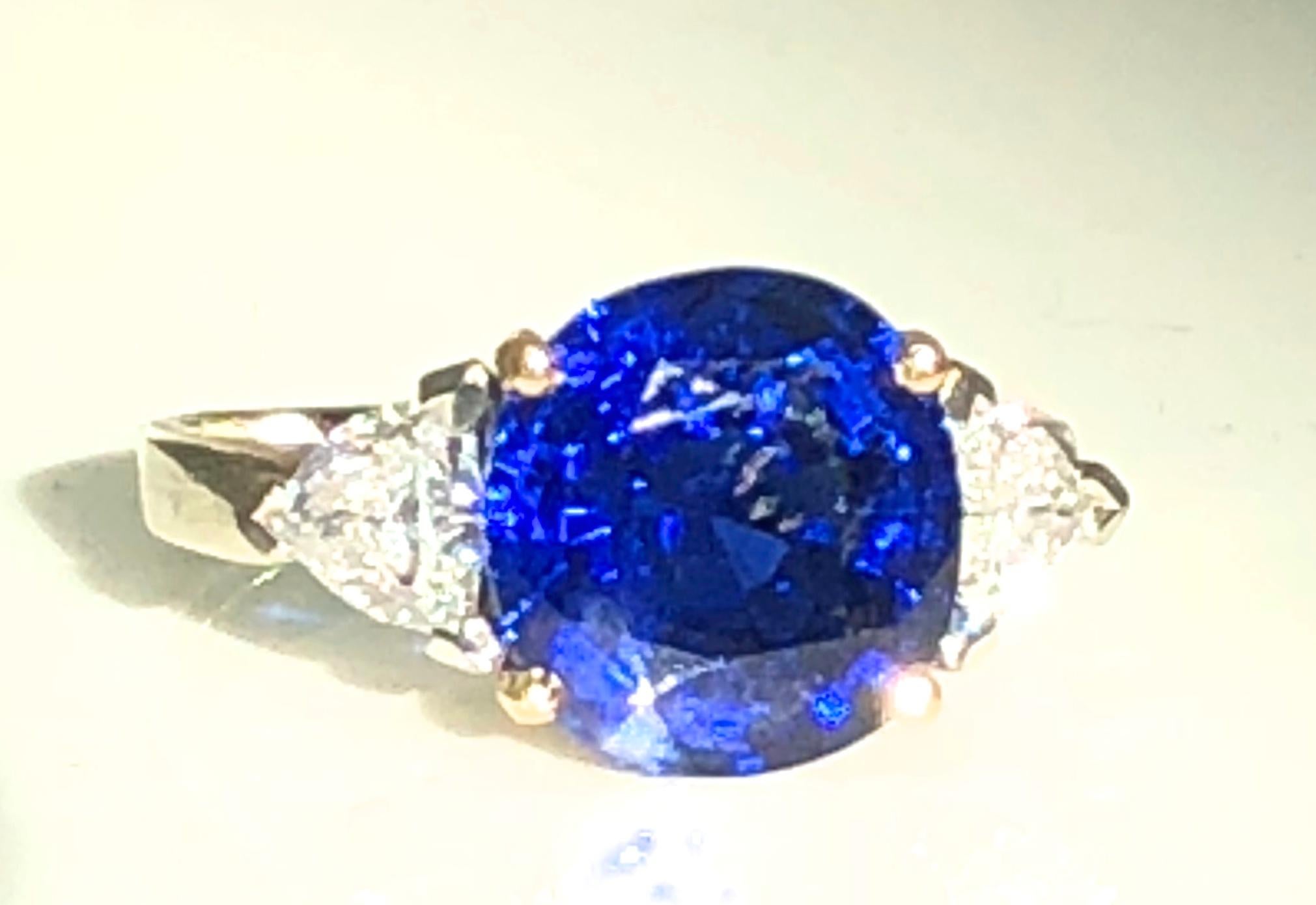 A Fine Burma Sapphire and diamond ring, mounted in 18ct white gold with a yellow gold collet. This stone weighs 4.82 carats and id flanked by two trilliant cut diamonds.
It is certified by the SSEF of Switzerland as and Anitque cushion cut sapphire.