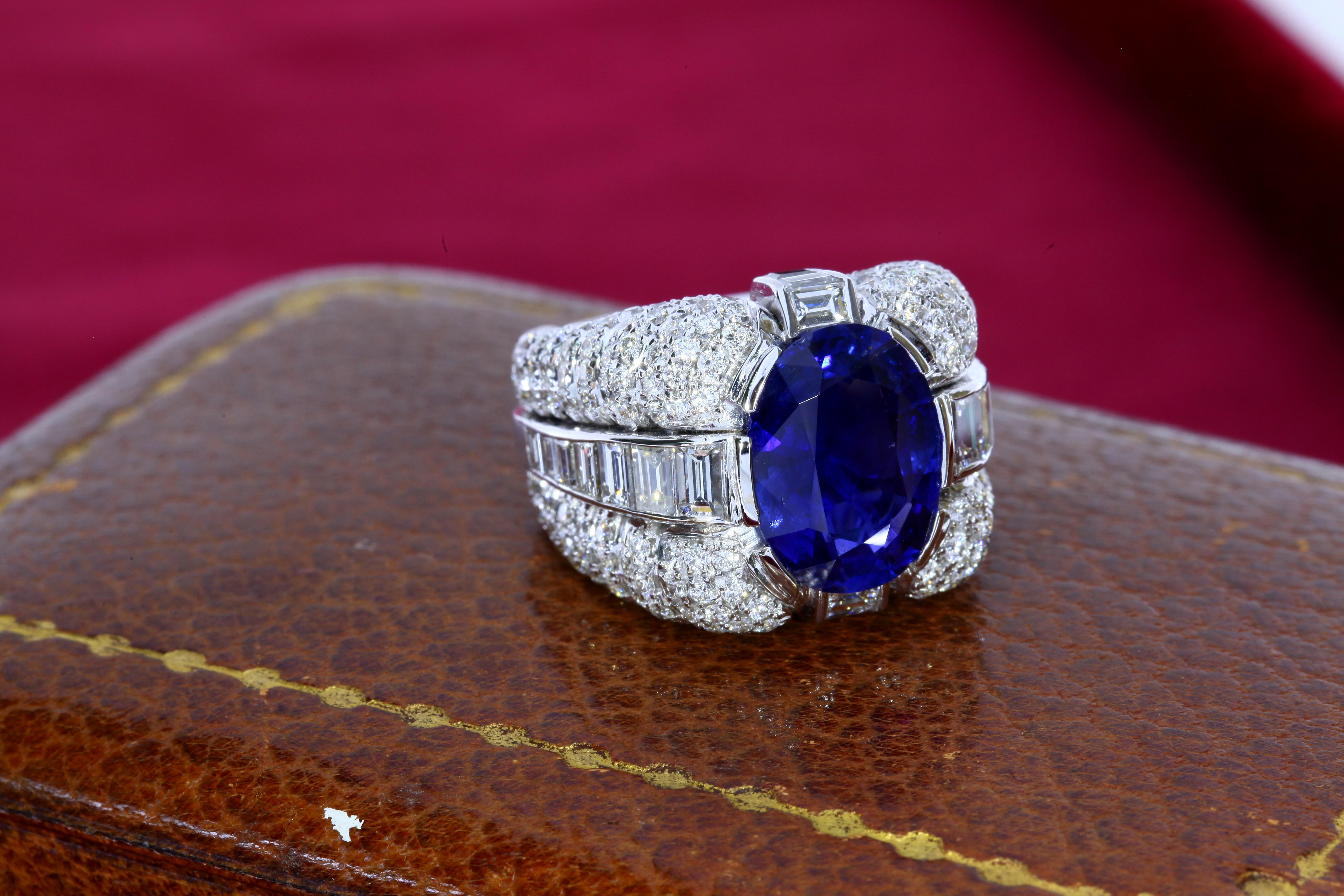 The 6.09 carat oval shaped sapphire of Burmese (Myanmar) origin is untreated and certified by SSEF. The stone is set in a large white gold ring clad with round- and baguette- cut diamonds. The ring has a weight of 24 grams and is size 53 (European