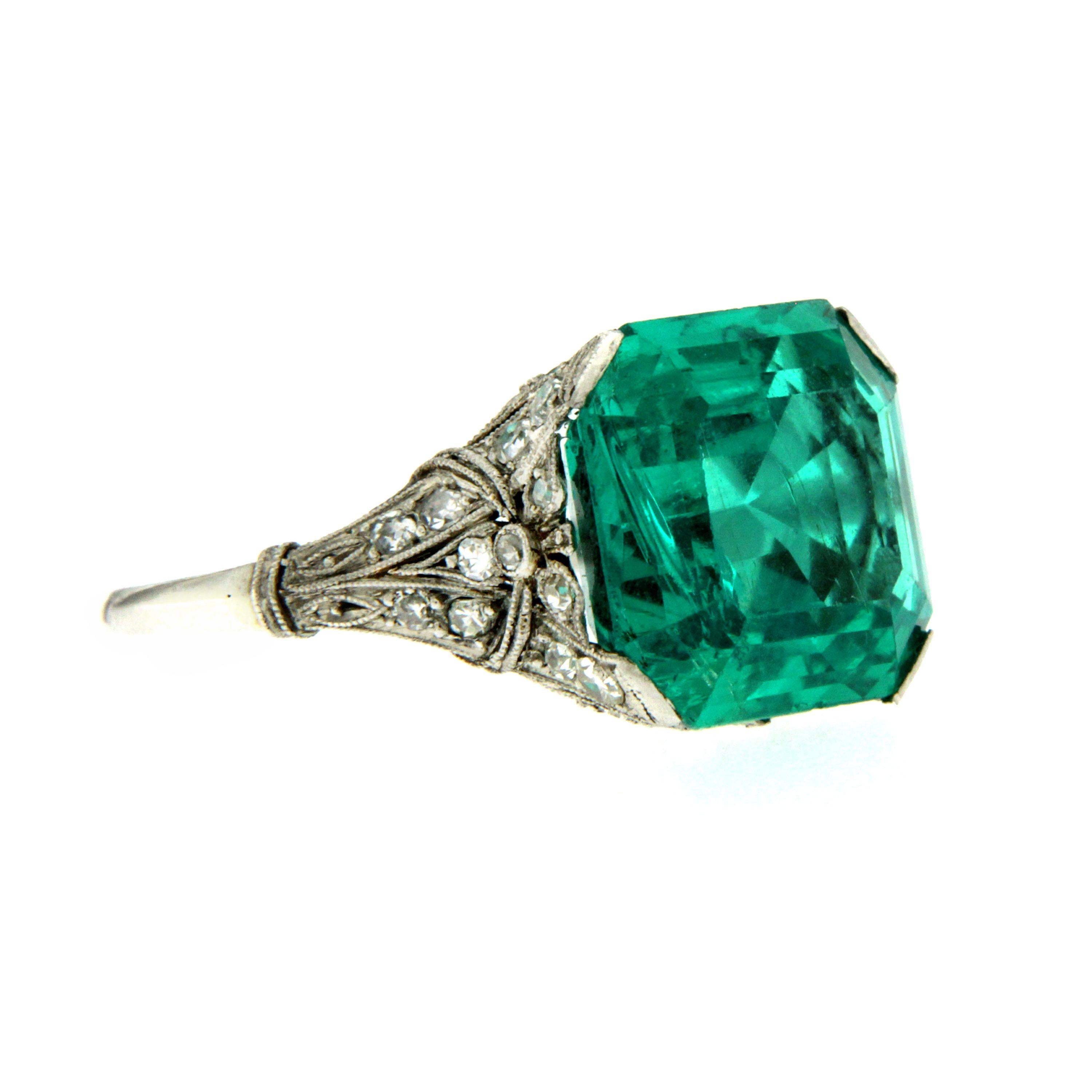 An exquisite filigree ring set in Platinum, authentic from Art Deco era, featuring a rare vivid 7.85 ct Emerald-cut Colombian Emerald, surrounded by 0,30 carats of old cut diamonds. 
The Emerald is accompanied by a SSEF certificate nr. 99311, Ssef