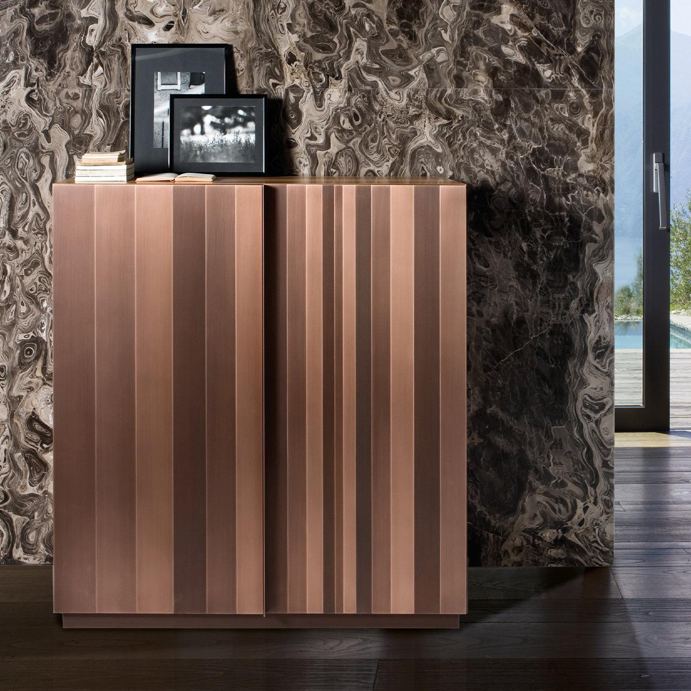 This bright and sophisticated sideboard is a superb solution for complementing modern homes. Copper stripes in different sizes and finishes cover the plinth base, sides, and front doors, which open to reveal an ample storage unit veneered in