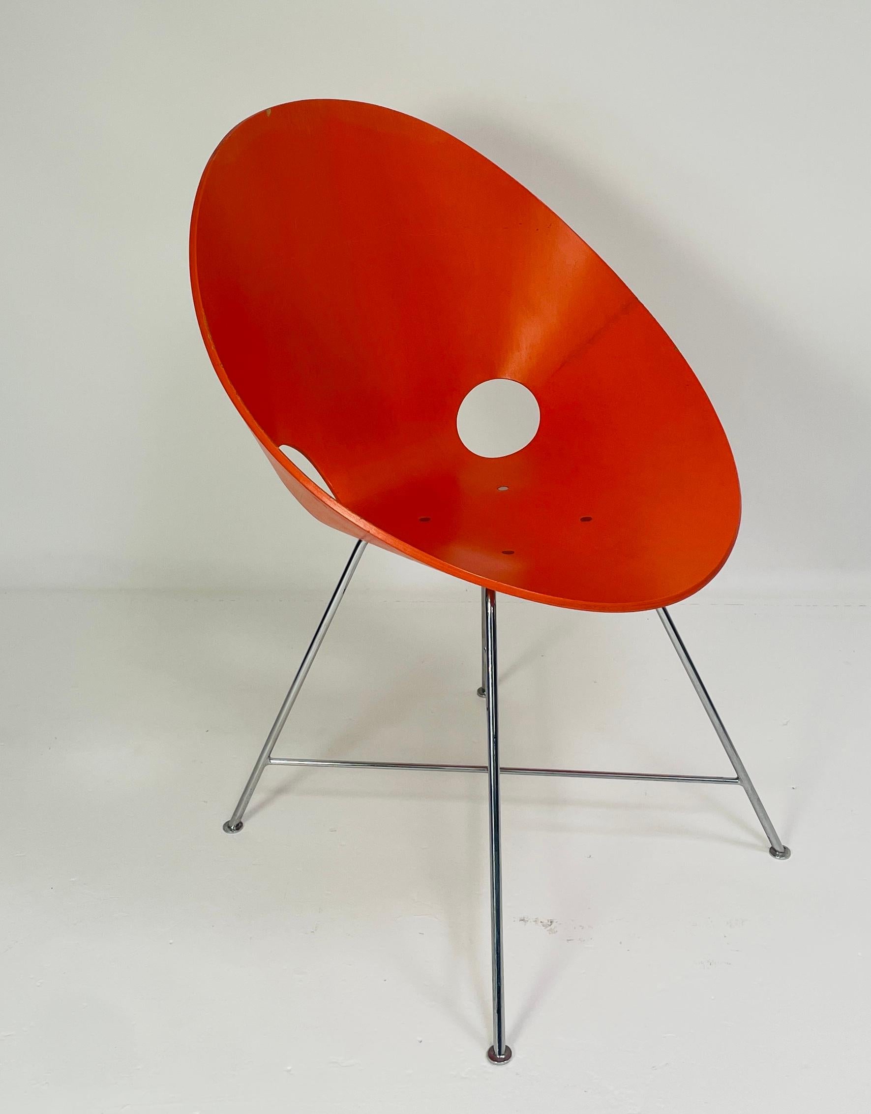 The ST 664 chair designed by Eddie Harlis in 1954. Thonet manufactured the chairs in Germany. These chairs are no longer produced. The chair has an orange painted finish and are made from bent plywood (beech). The legs are chromed steel. In good