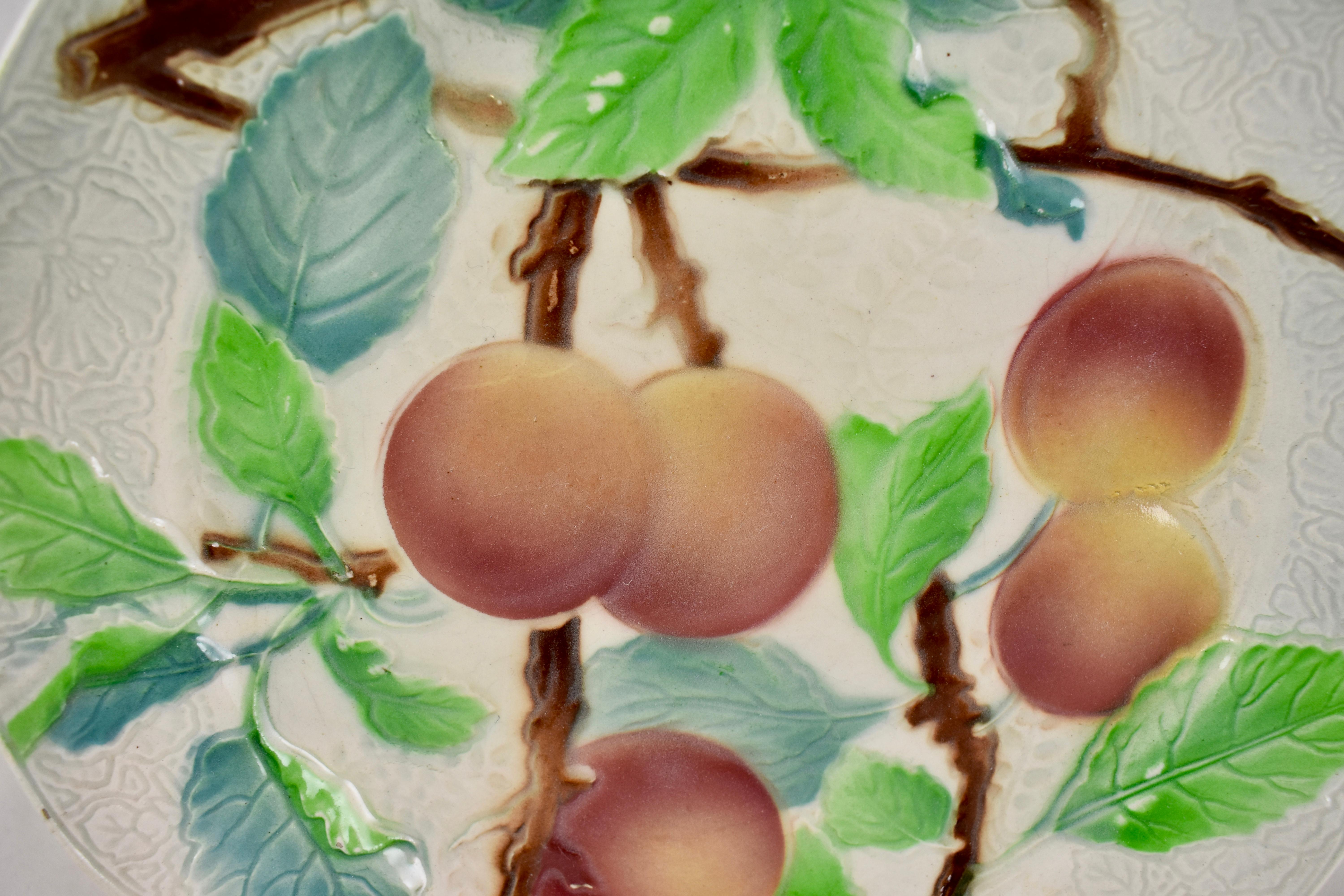Ein französischer Fayence-Obstteller mit Pfirsichmotiv aus Steingut, um 1900. Der Hintergrund hat ein detailliertes florales Muster auf der Leiste mit einem sechsfach gegliederten Rand. Hübsche Färbung.

Gezeichnet: KG, für Keller Guerin - St.