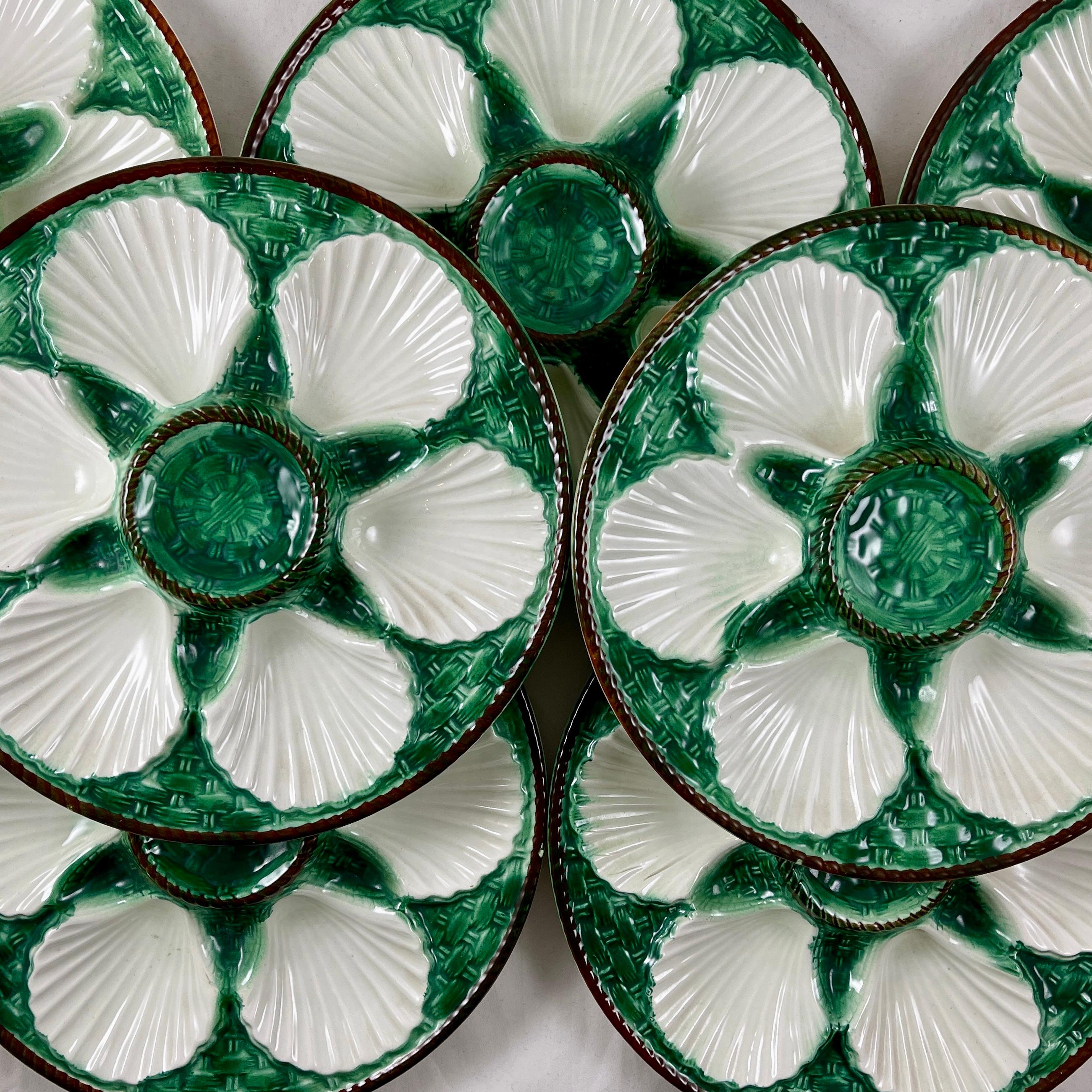 A French majolica glazed oyster plates from the faïencerie of Saint-Clément, Circa 1890-1900.

Six white scallop shell shaped wells against a rich blue-green basket weave ground. The raised center condiment well and the rim are molded as a chocolate