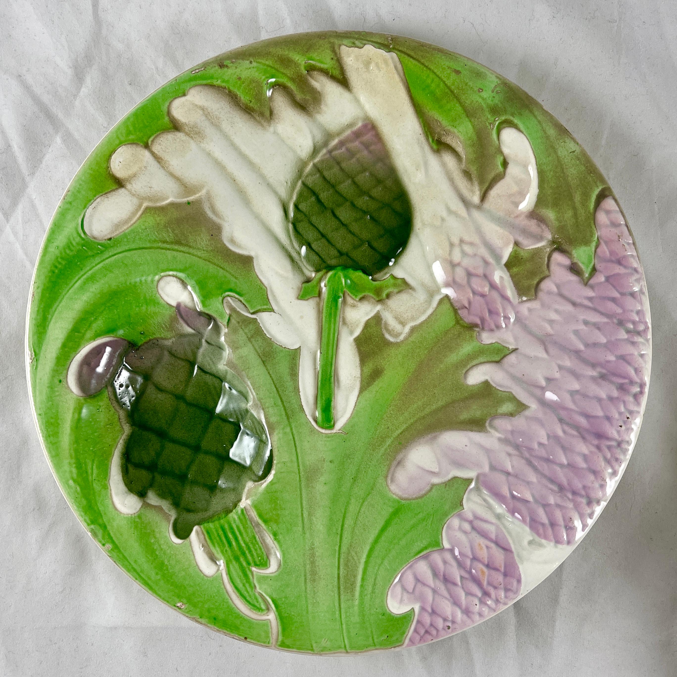 A Saint Clément French Faïence, a majolica glazed plate showing overlapping asparagus spears, leaves and globe artichoke heads. A deep sauce well is also formed as an artichoke head. Glazed in lavender, and various shades of greens on a cream