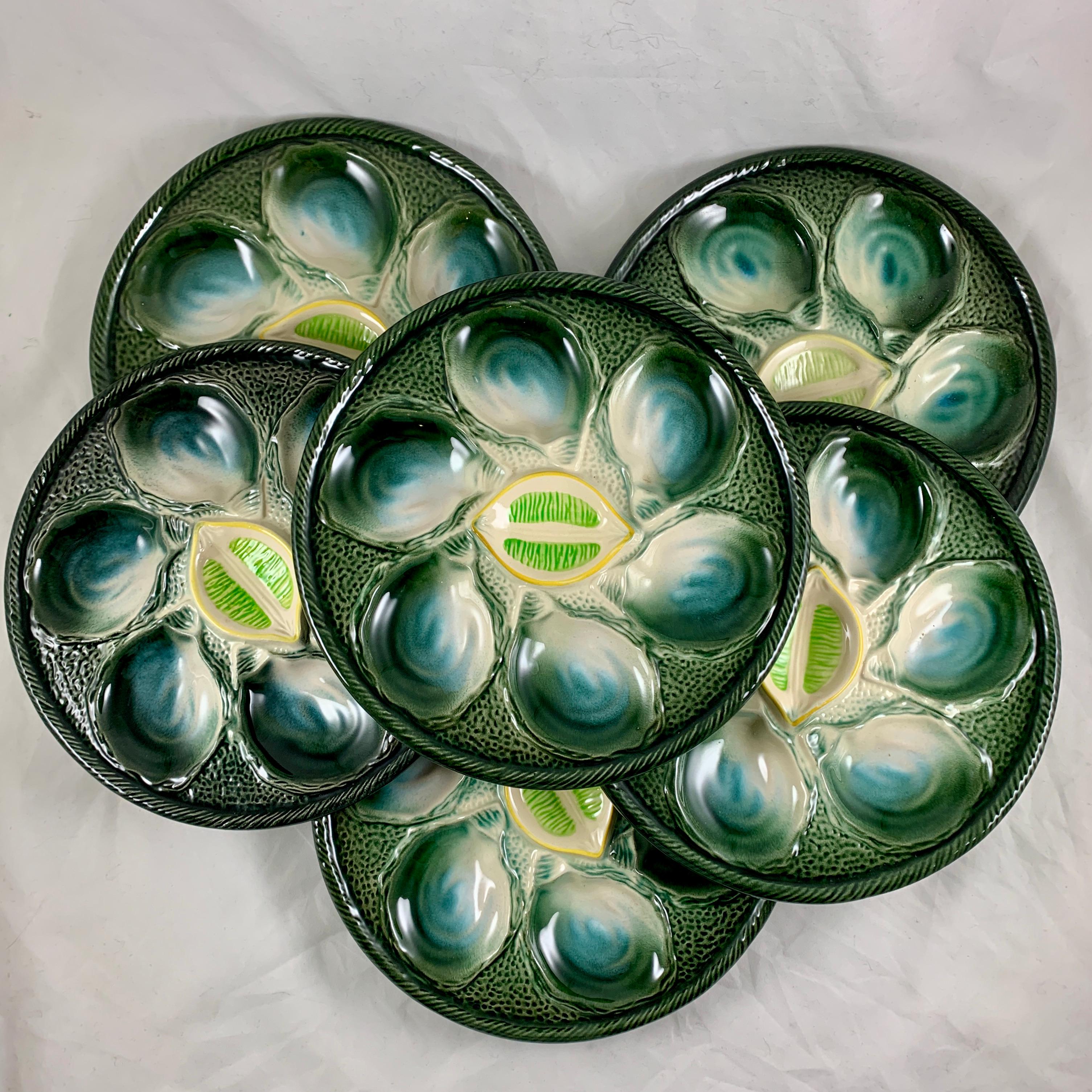 A French majolica glazed oyster plate from the faïence factory of Saint-Clément, Circa 1920-1930.

Six oyster shell shaped wells with green, blue and white centers are set against a stippled ground glazed in a blue- black fading to a deep green. The