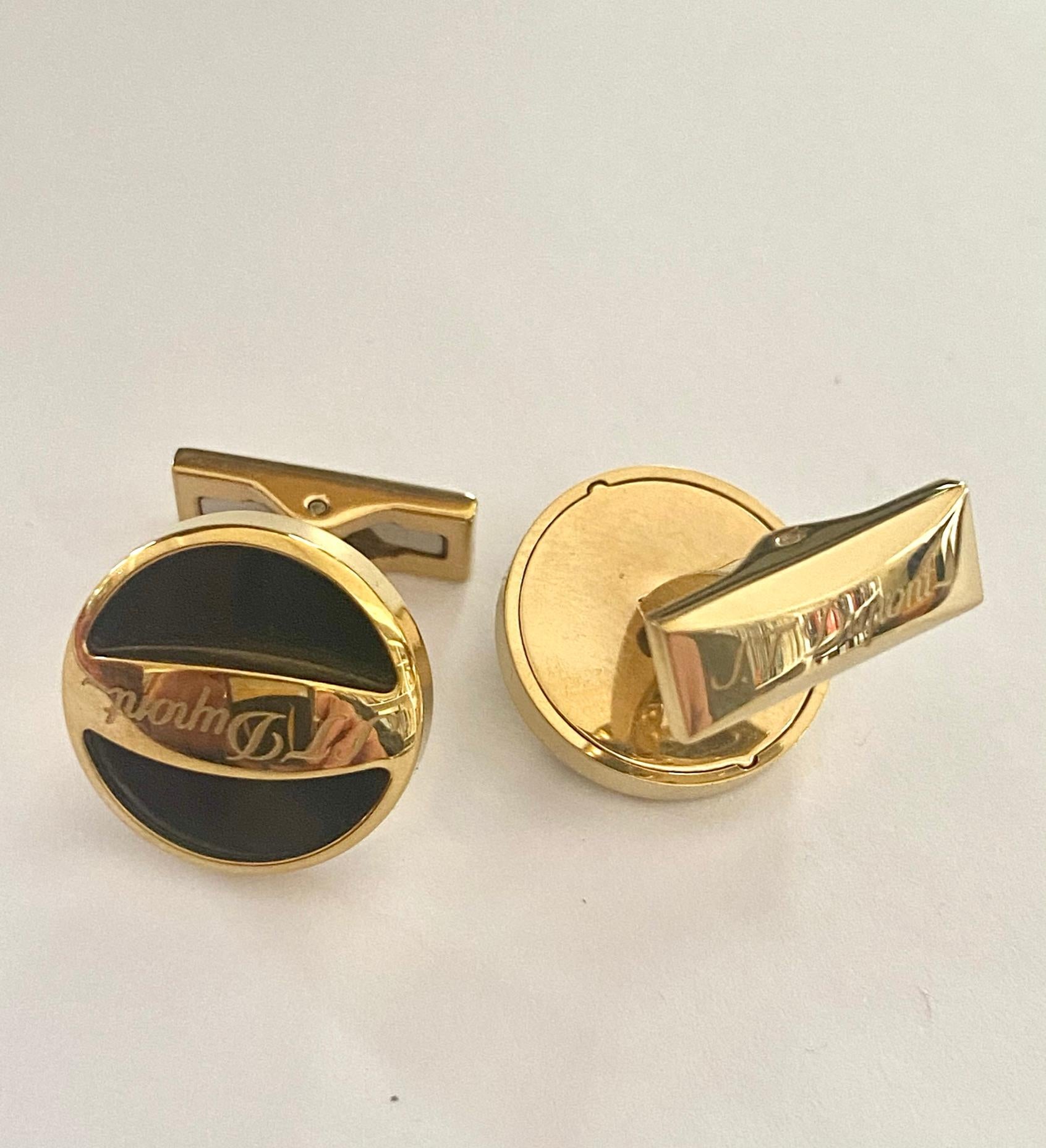 A pair of gold plated cufflinks.
Brand: S.T. Dupont Paris.
round model with black background, signed twice.
product no; 005791
diameter 18 mm.
height 6 mm.
distance between front and back total: 24 mm.
Weight: 18.69 grams
N.O.S. new old stock.
Comes