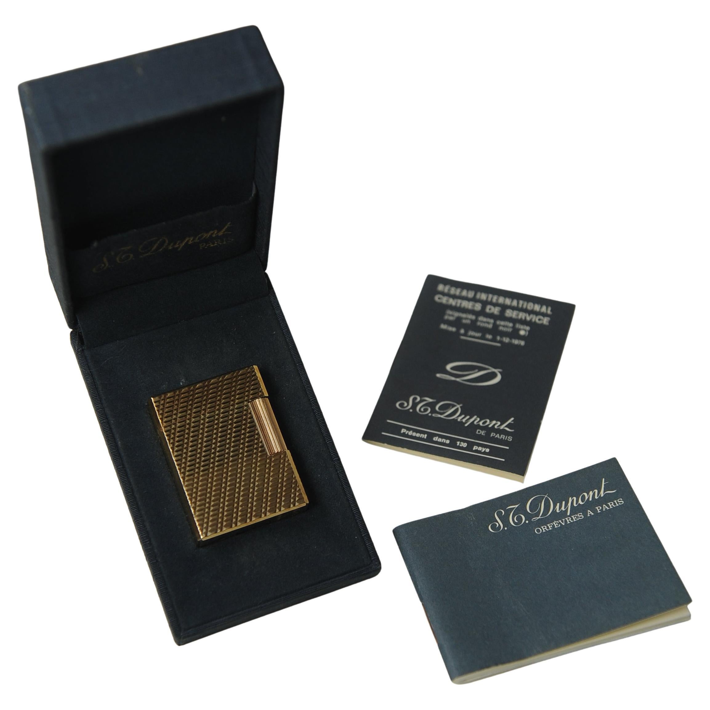S. T. DuPont Ligne 1 Small Paris Cigarette Lighter with Machine Turned Design in Original Blue DuPont Box With Paperwork 

Stamped S. T. DuPont Paris, Made in France 
Informational Booklet 1976 
Serial Ref G8BG87

Lighter dimensions Height 4.7cm I