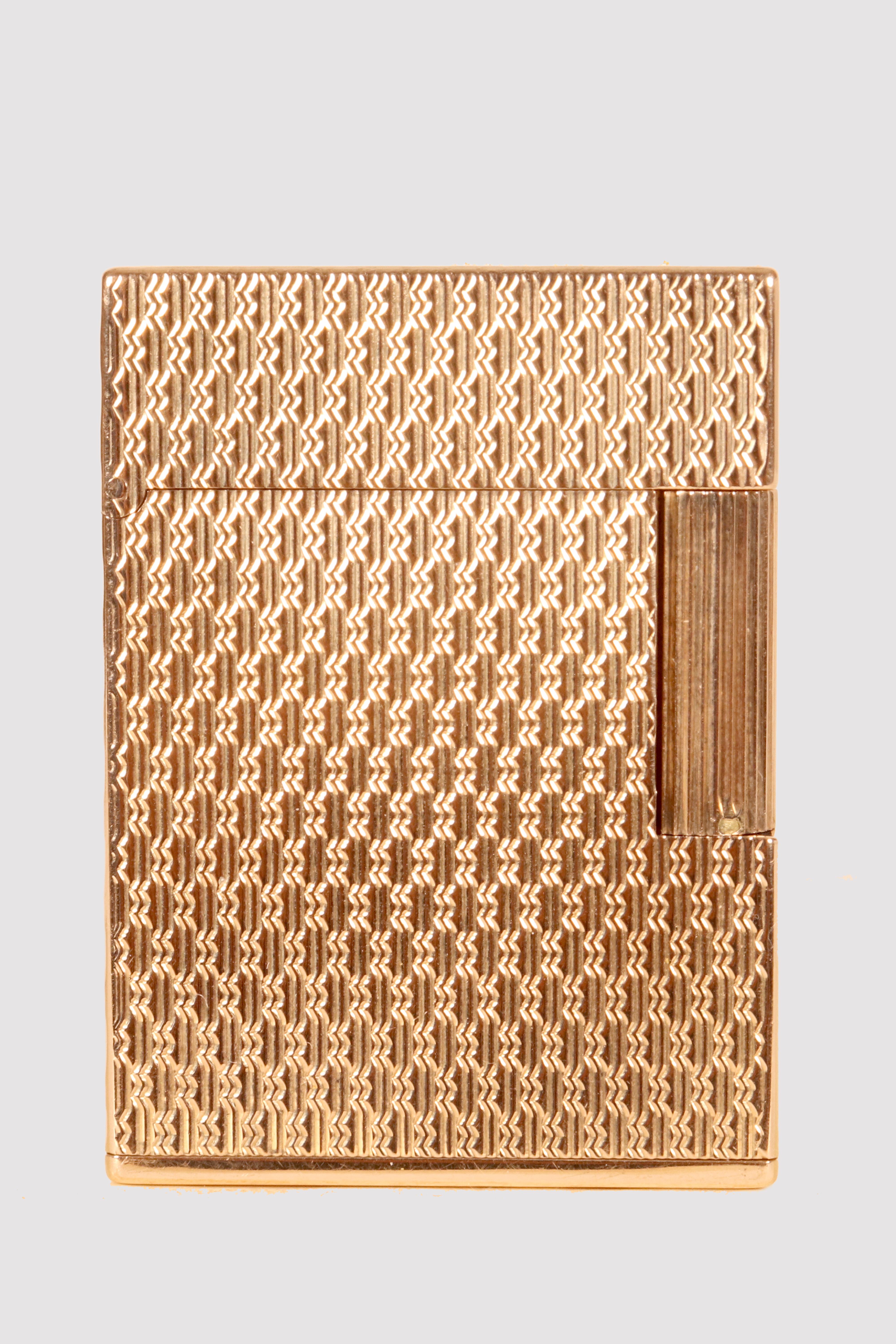 Il T.S. L'accendino Dupont è realizzato in oro giallo 18 kt e appartiene alla linea 1, modello B 1808. (Peso 108 gr. 0,239 lb.) Sul fondo si legge S.T. Dupont, Parigi, prodotto in Francia, B 1808, 18 kts. Decorazioni in rilievo lungo tutti gli altri