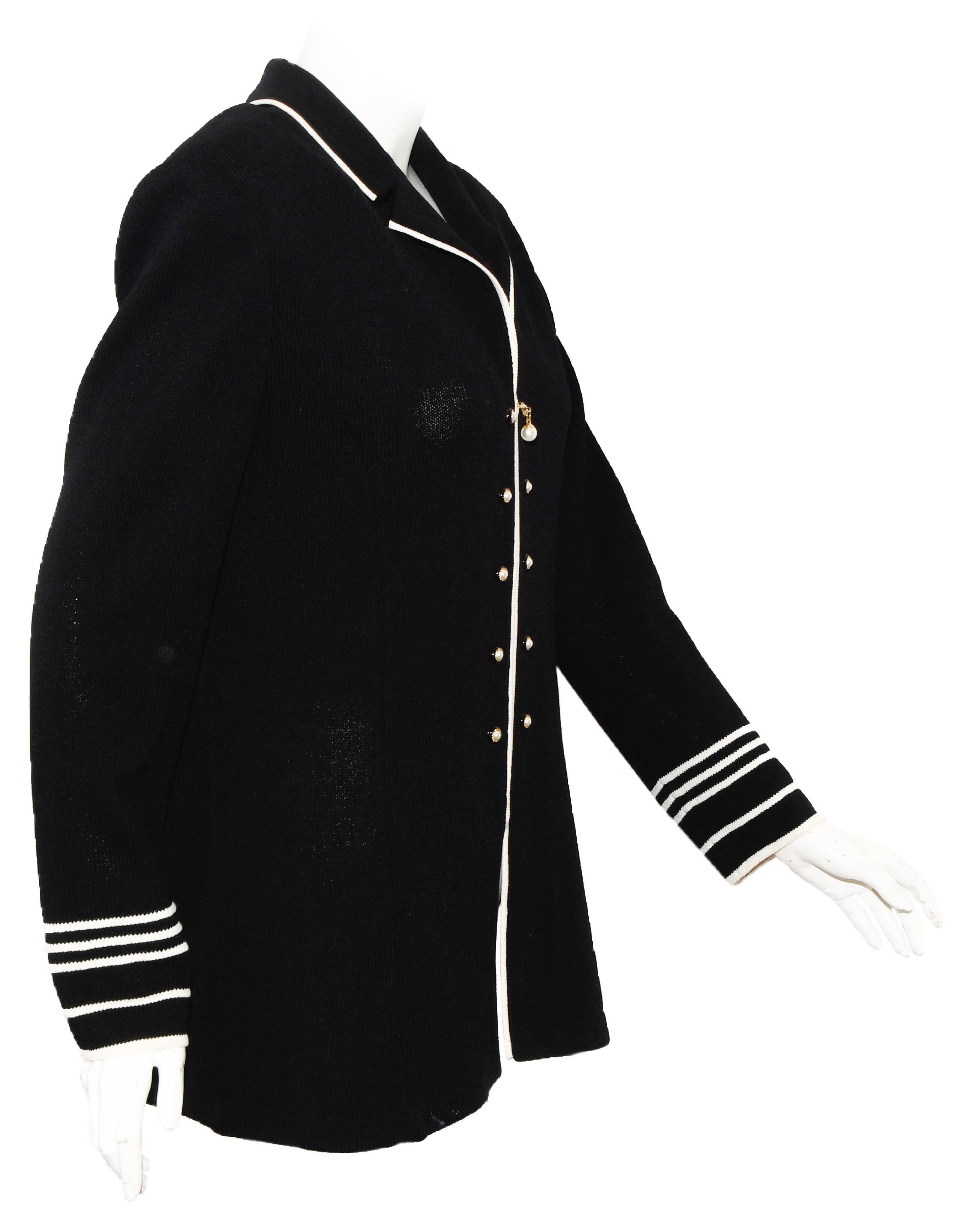 St. John black knit jacket includes faux pearl buttons on both sides of the zipper at front.   This jacket flaunts contrasting white piping that frames its refined knit texture. Tailored and finished, this is a wardrobe essential with a rich