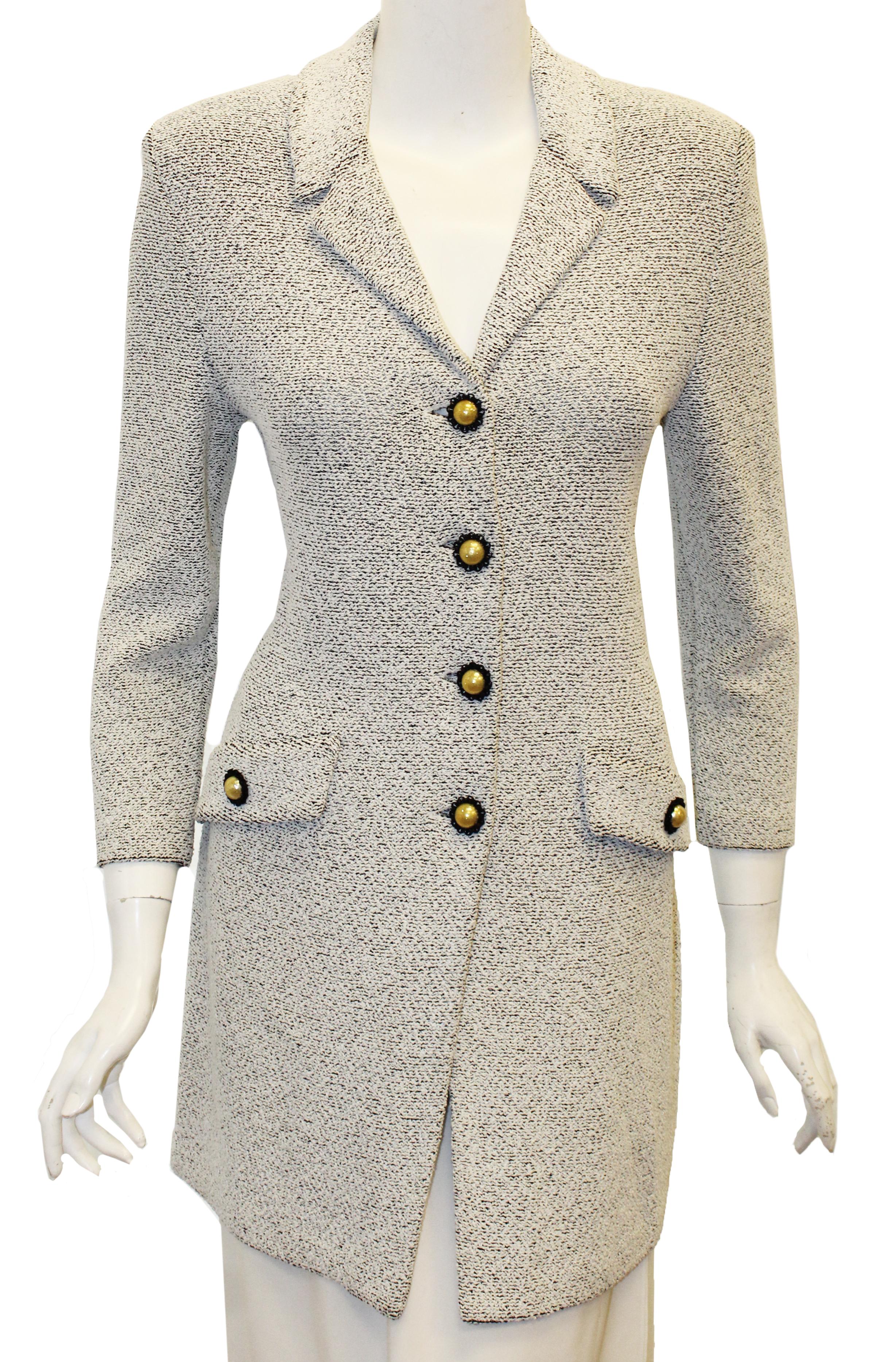 St. John black and white long jacket includes looped fringe collar.  This jacket has 2 front faux flap pockets at front with a St. John faux pearl  button.  For closure, 4 additional buttons are included.  This jacket is not lined and is in