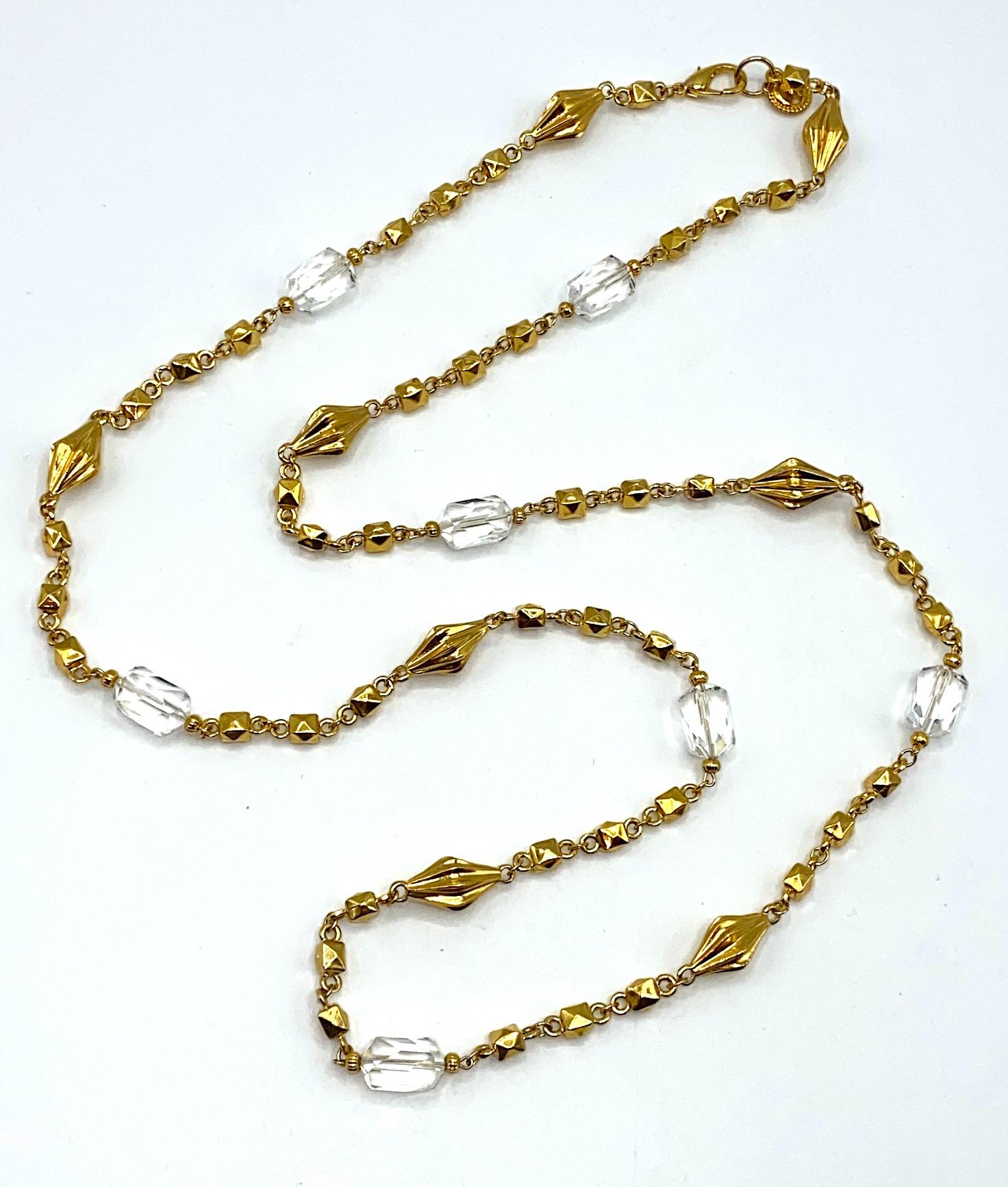 A lovely St. John Collection gold long necklace with clear crystal beads circa 1990. The chain is a mix of gold round links, pointed cube links and fluted round diamond shape gold plated beads. Additionally, the necklace has seven multi faceted