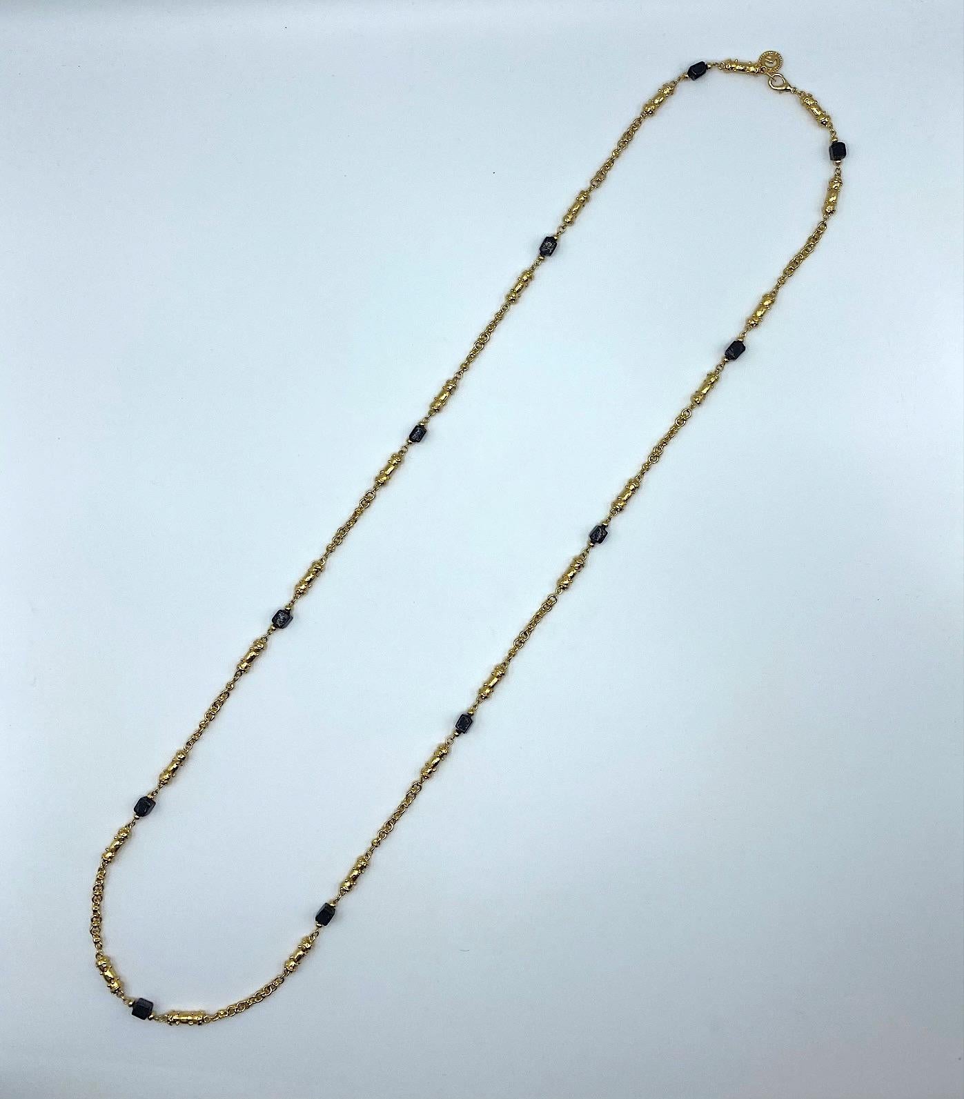 St. John Collection classic gold long necklace with back glass beads circa 1990. The chain is a mix of gold plate round links, cast gold beadwork long links and hand formed black glass cube shape beads. Each glass bead is unique and different
