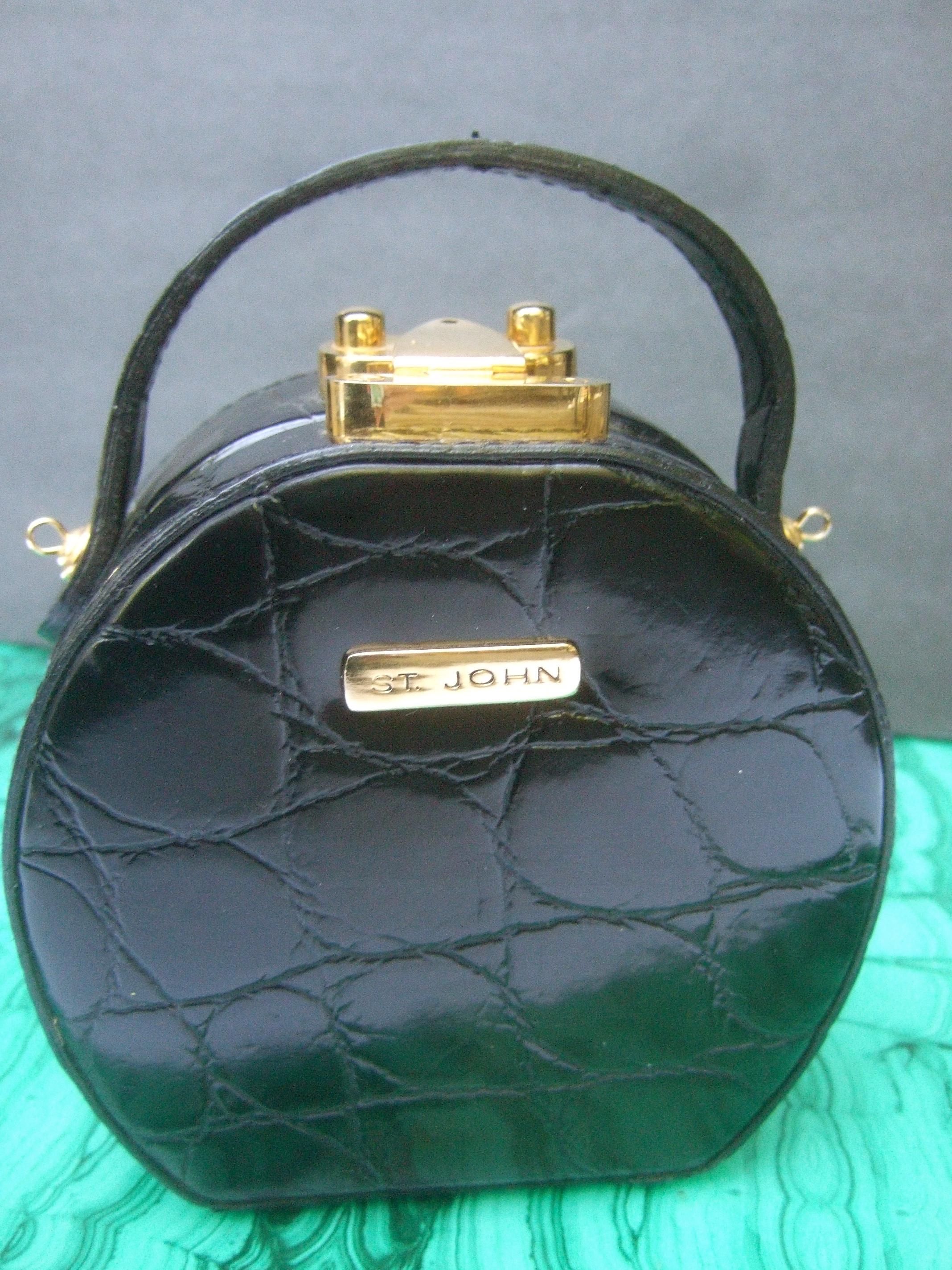 St John embossed vinyl diminutive size handbag - shoulder bag c 1990 
The stylish compact size rounded purse is covered with embossed patent 
black vinyl that emulates reptile skin 

Designed with a sleek gilt metal latch clasp mechanism. Adorned