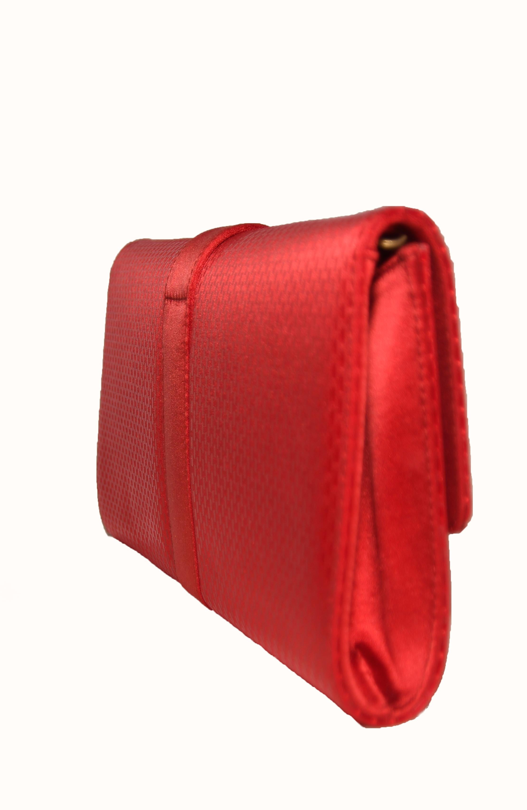 St. John red sequined clutch contains a removable gold tone metal shoulder strap.  The interior pocket is lined in red satin and includes a small side slit pocket with St. John gold tone plaque on the pocket.  For closure, a hidden magnetic snap