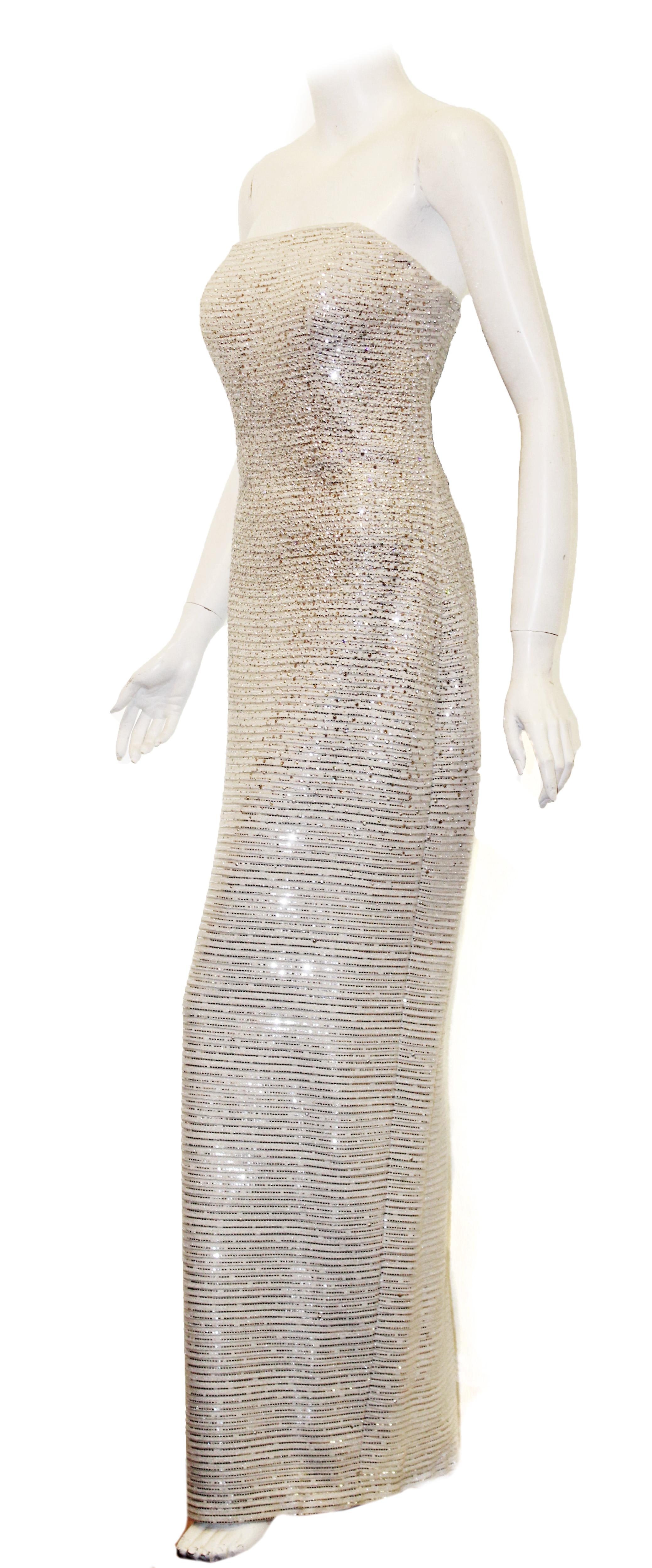 St. John white lattice knit gown interlaced with mini silver sequins and crystals throughout the dress creates a sparkling, signature sophisticated piece.  This strapless gown contains an attached internal bustier for added support.   Gown contains