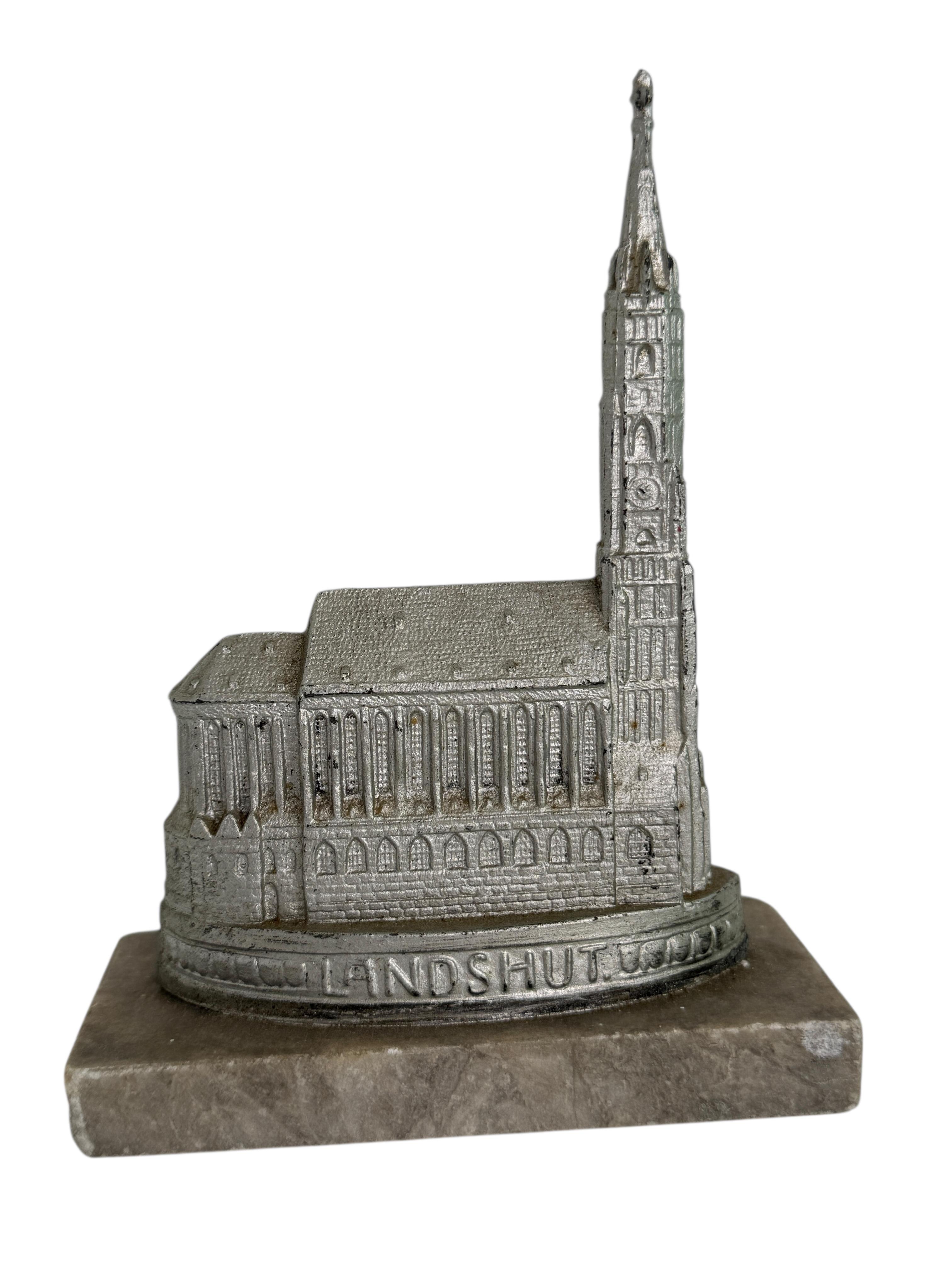 Une sculpture décorative de bâtiment en souvenir de la ville de Landshut en Bavière. Elle montre l'église Saint Martin. Quelques usures avec une belle patine, mais cela est dû à l'âge. Fabriqué en métal avec une base en marbre. Cet objet a été