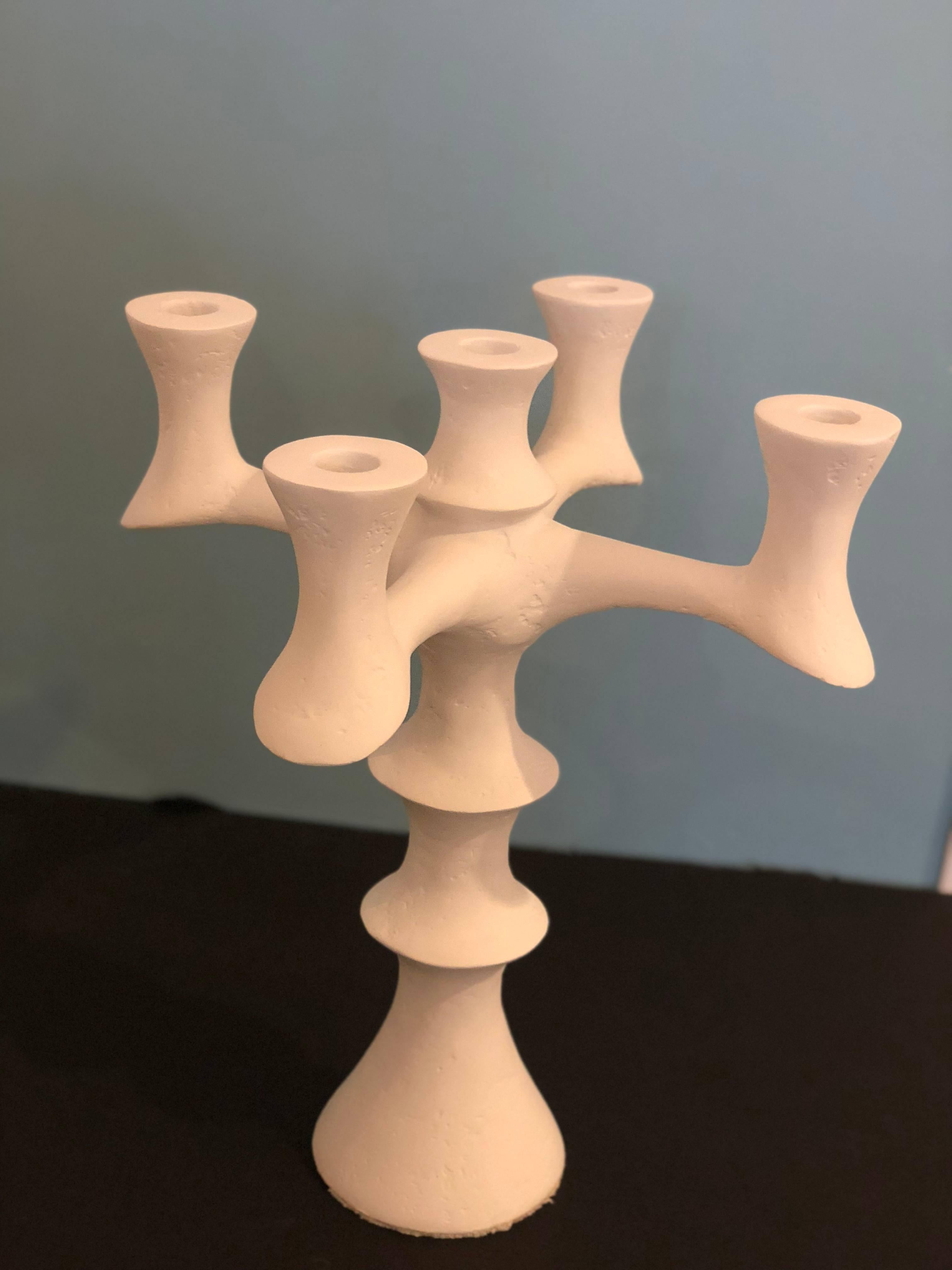 Sculpted plaster of Paris candleholder. A reminiscent of Giacometti's work, this five candleholder has a sleek yet elegant design. With its soft edges and texture it makes for an outstanding centerpiece for any console or table. Candleholders have