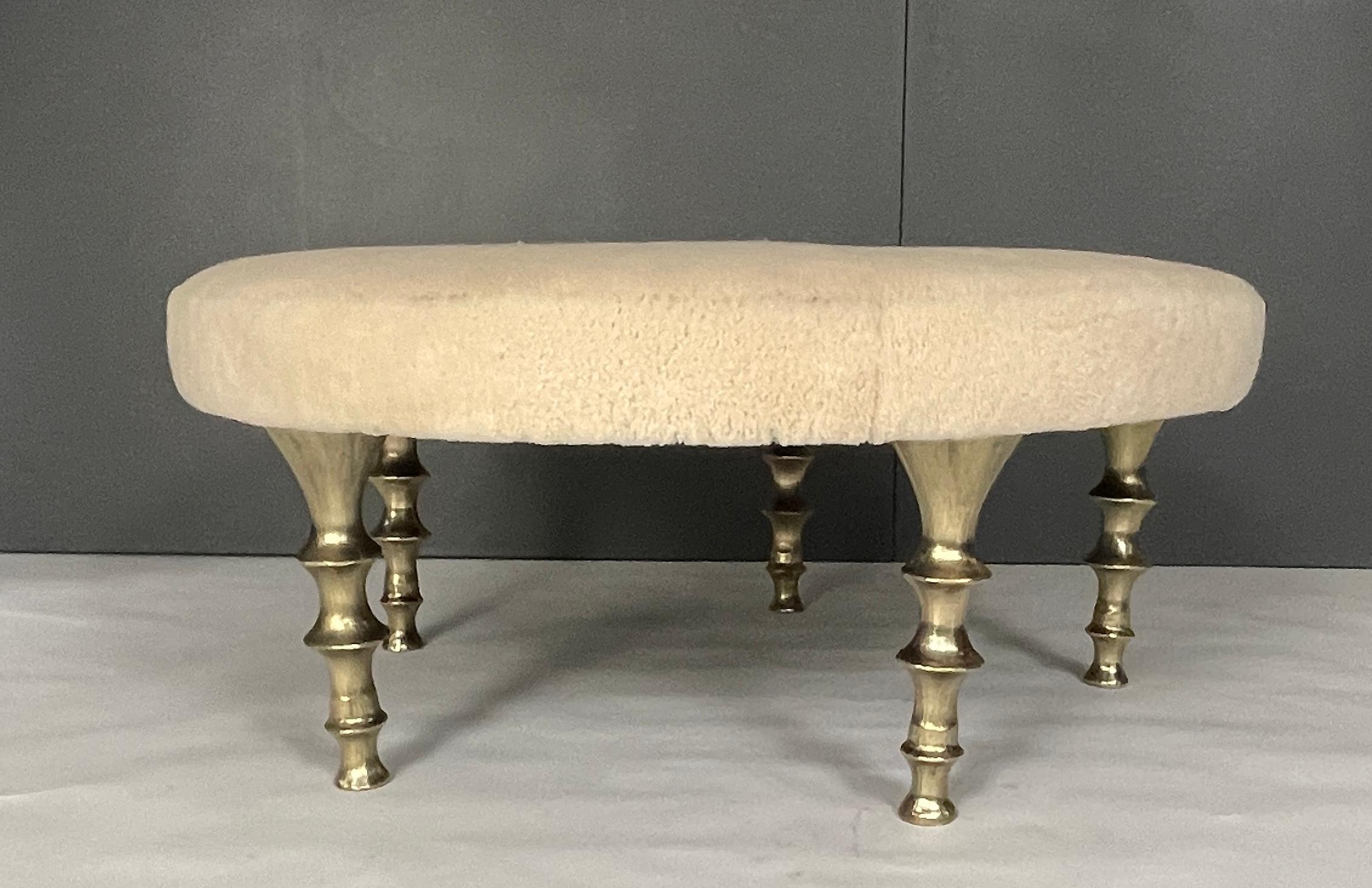 This round ottoman make a dramatic statement in your interior. It has five powerful cast gold bronze legs, shearling hide with an organic feel. The cushion can be made is various shapes, in your own fabric or hide. We can also create stools or