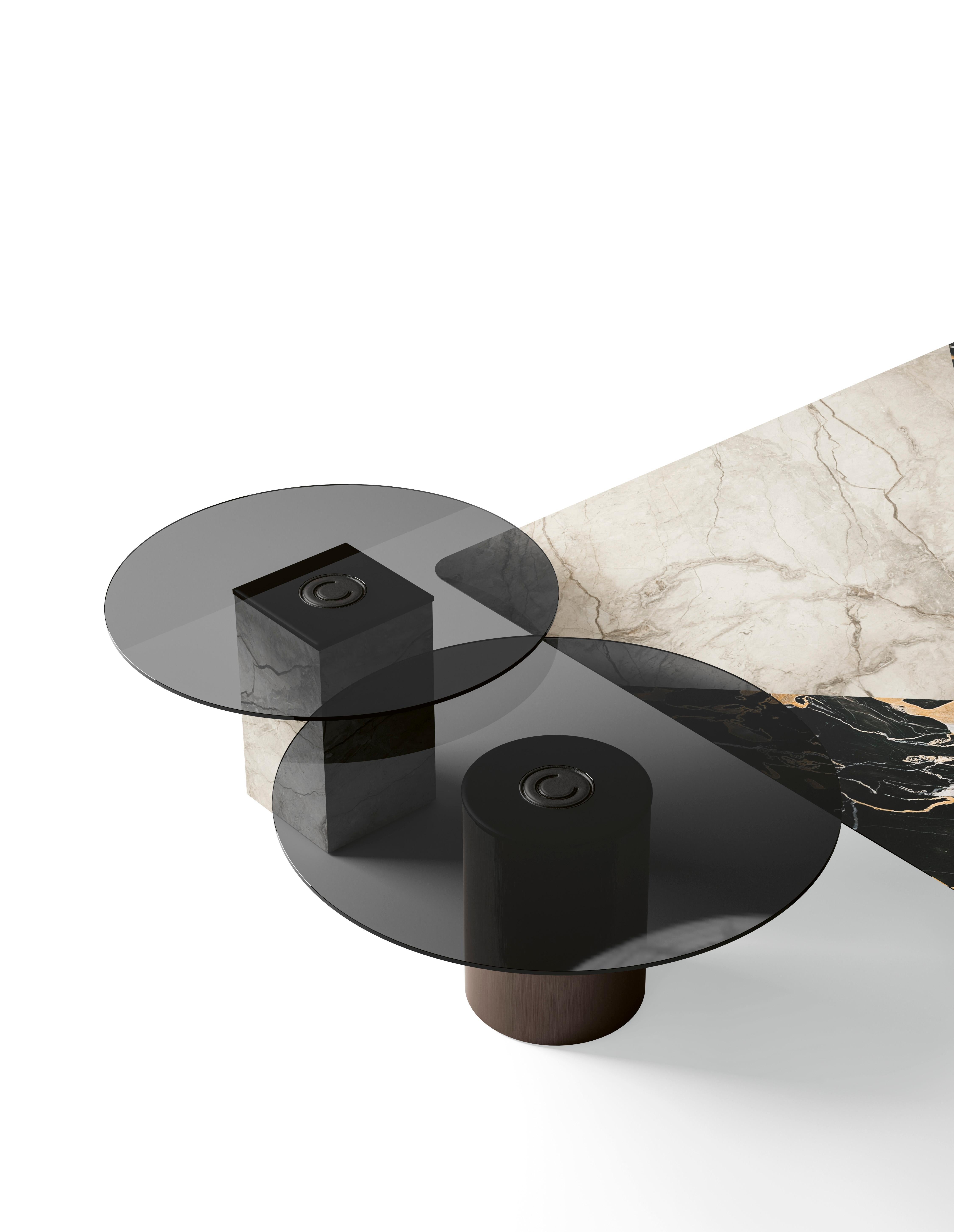 Table basse dotée d'un plateau en verre fumé élégant, complété par un piètement en métal qui constitue une base moderne et solide. Le design est encore rehaussé par des détails en cuir sellier, qui ajoutent une touche de sophistication et d'élégance