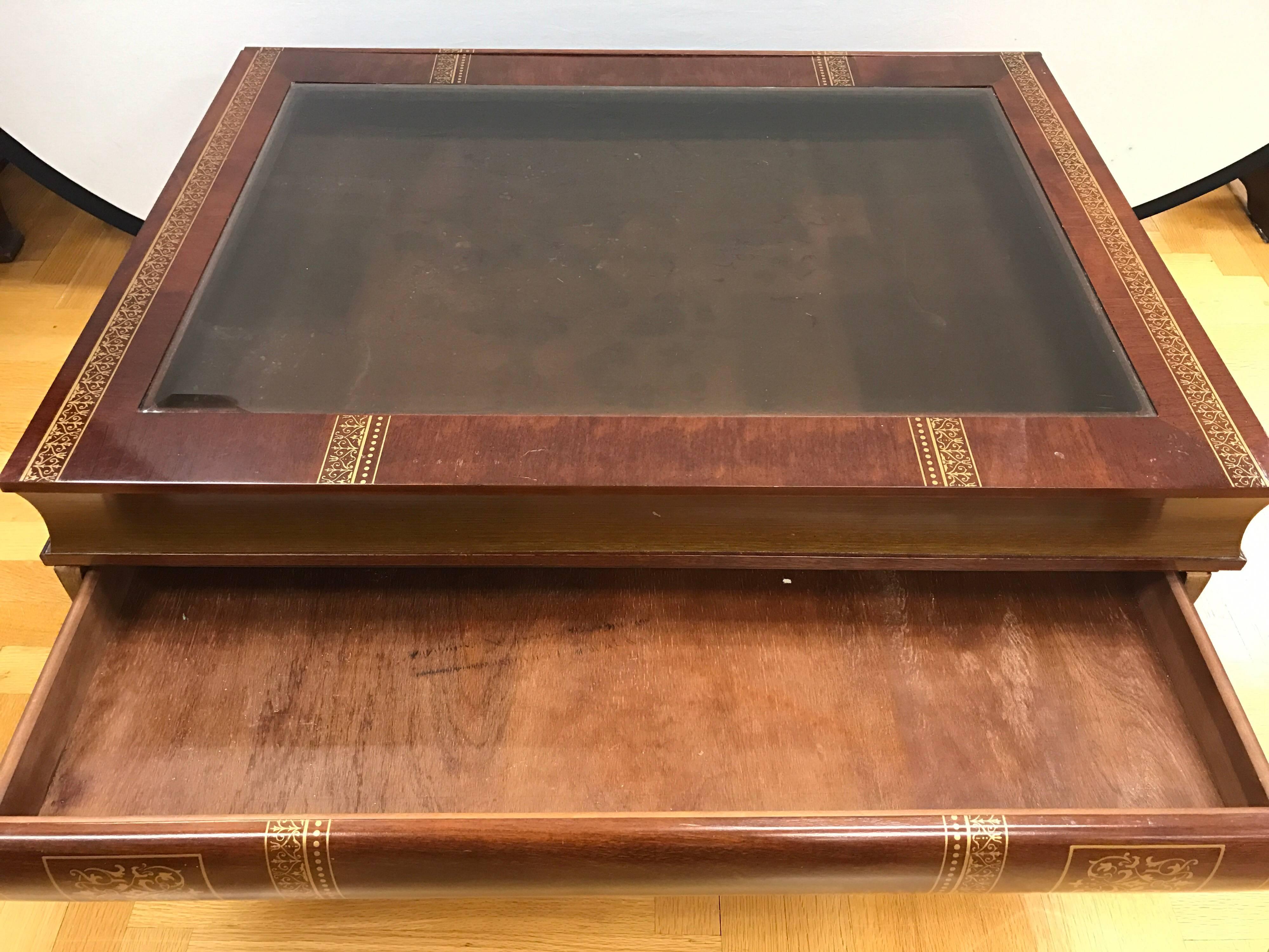 Made to look like a stack of books, this cocktail/coffee table has three large drawers that open to address your storage needs. The top drawer is felt lined and is visible due to glass inset at top and can be used to display small collectibles or