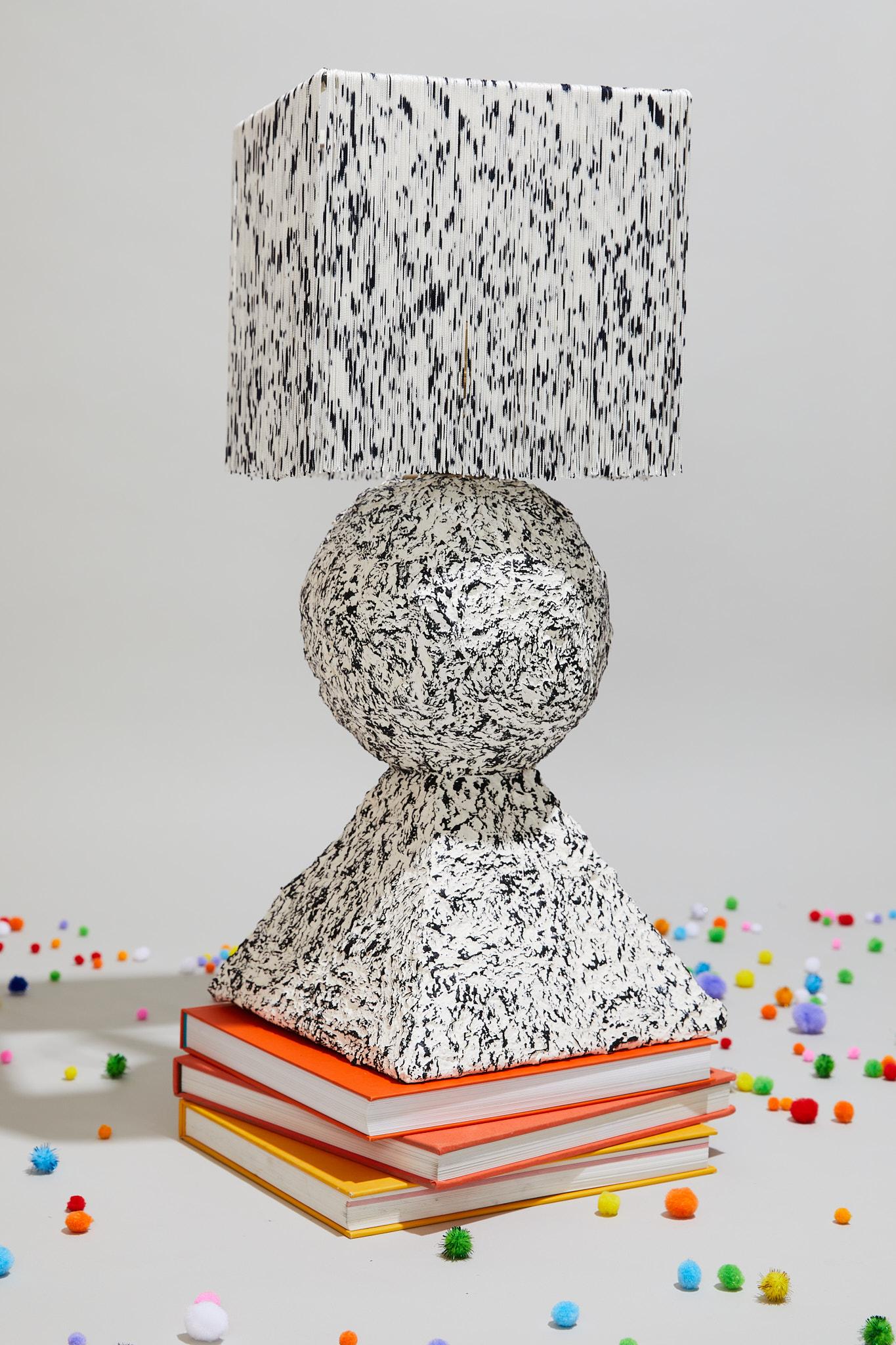 Inspired by architectural elements, the stack lamp plays with balance and form of the fundamental shapes of building. Hand painted, patterned surfaces pair with hand-dyed and knotted fringe shades to highlight the ephemeral and playful qualities of