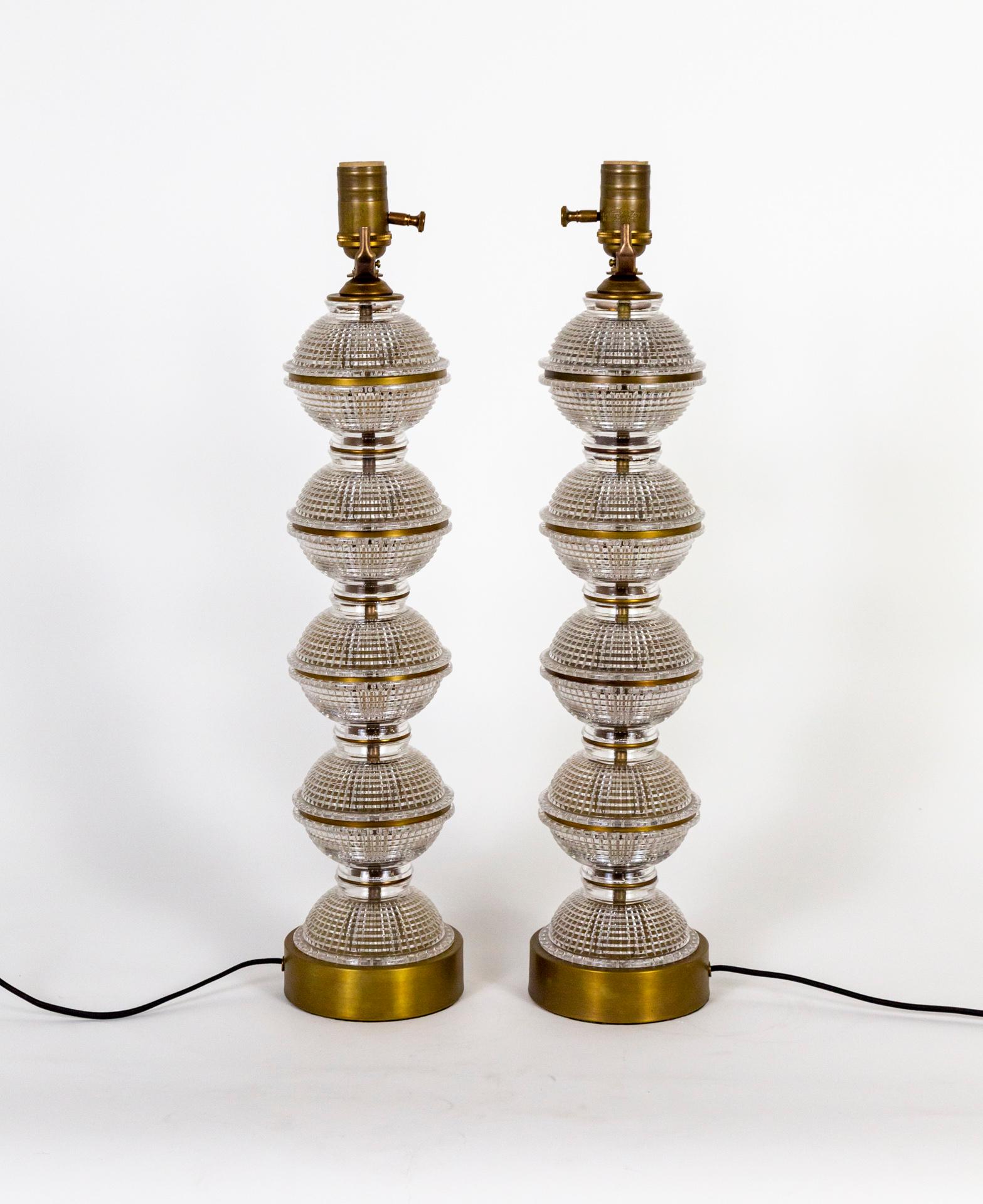 A pair of custom-made table lamps with antique, quilted glass forming spheres that are banded with thin, brass rings. They are stacked on a complimentary brass base, with sockets in matching tones. With dimmers on the sockets. Made with new brass