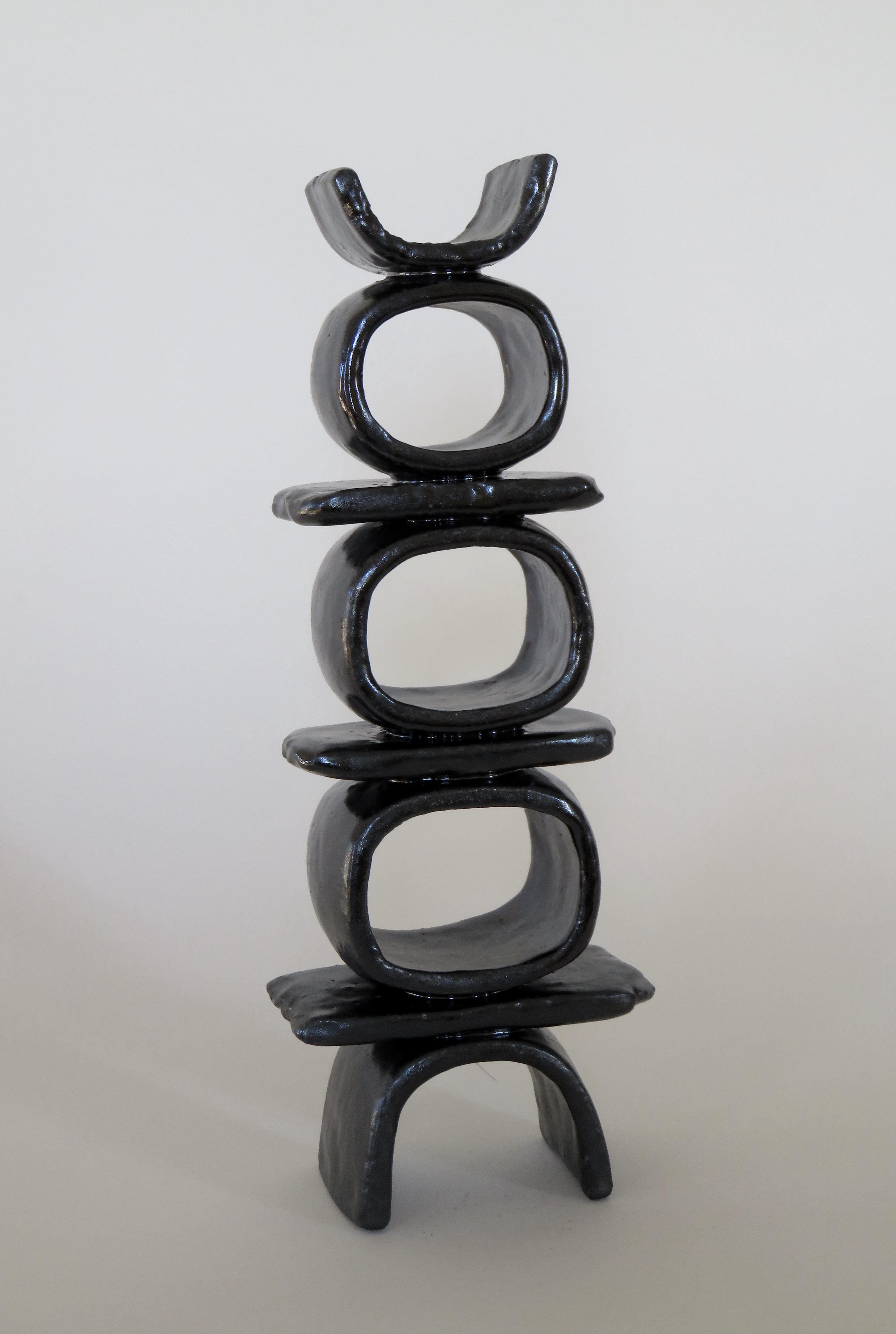 Totemic ceramic sculpture, three stacked rings and bars, on curved feet with curved topknot. Fully handmade, glazed in a glistening black. Signed with artist chop and signature.