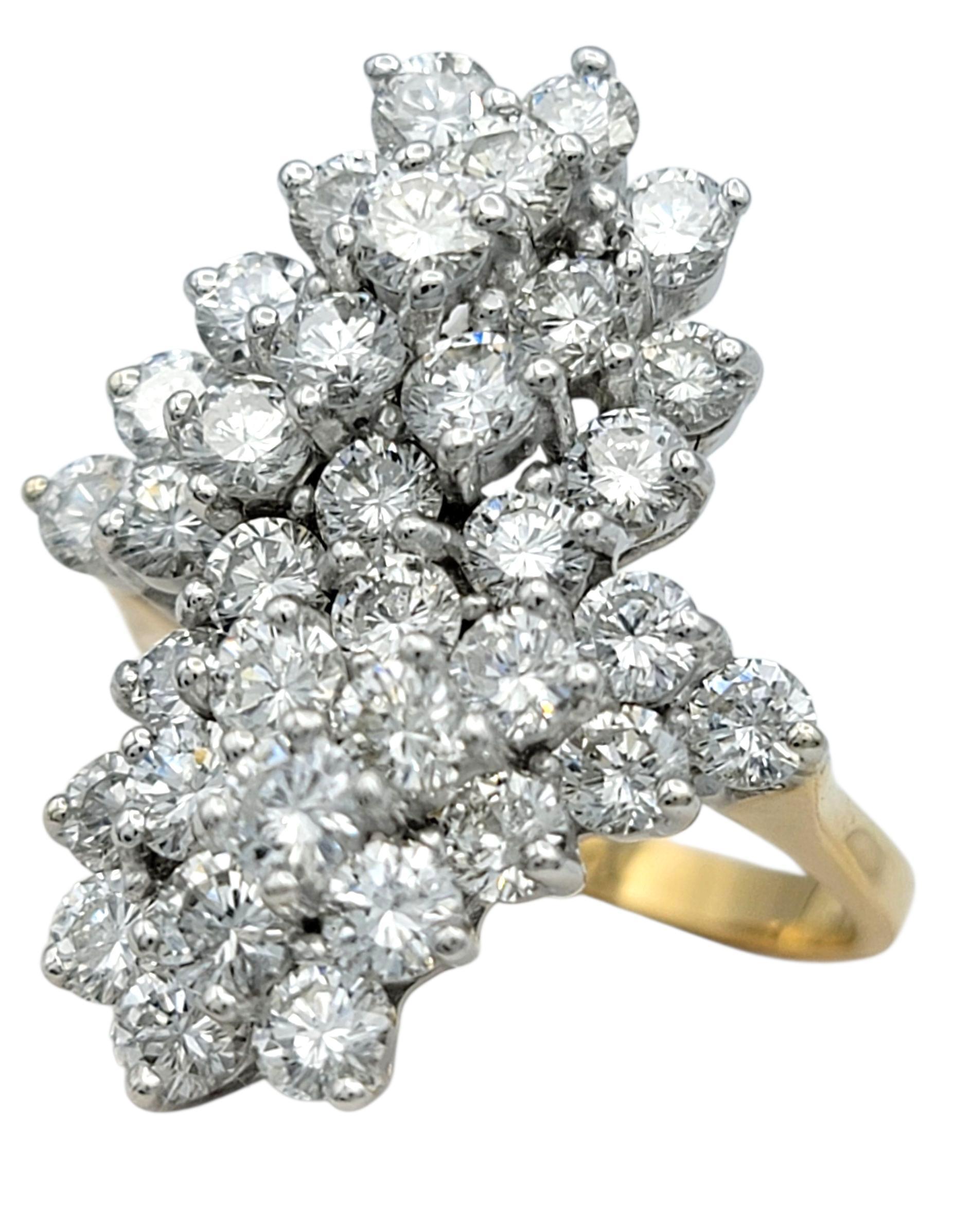 Questo anello di diamanti mozzafiato incarna brillantezza e movimento, disegnato in uno stile a grappolo floreale verticale che emana un'eleganza senza tempo. Incastonato in oro bianco e giallo da 14 carati, l'anello presenta una disposizione
