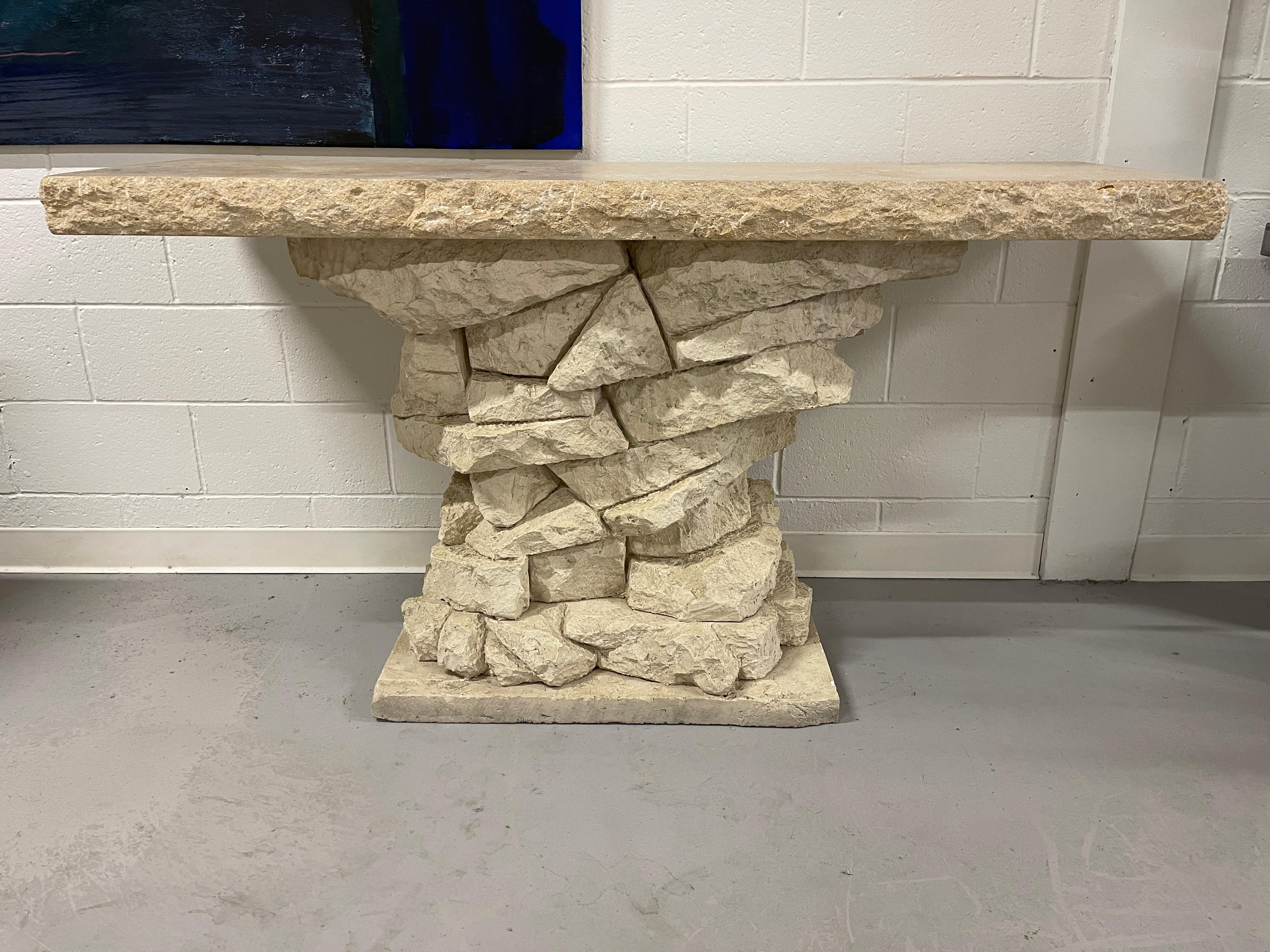 Wonderful faux stacked stone console table. The top is stone and extremely heavy. The base is some sort of poured or cast plaster. In good condition although there are some minor chips to the base under the overhang of the top. Some marks to the top.