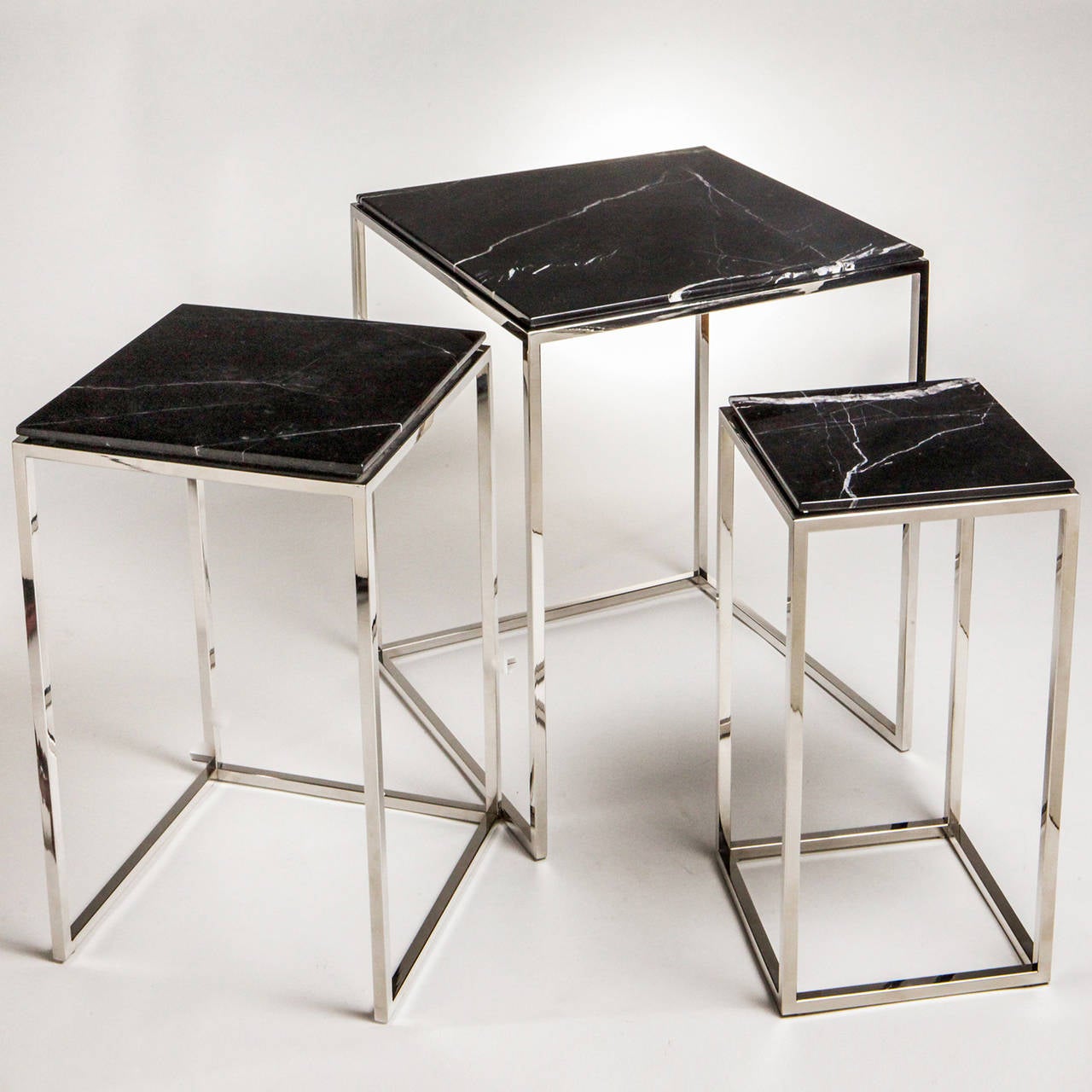 Set of three stacking tables with polished nickel frames and black variegated marble tops. Tables nest into each other from the tallest (H: 25.5