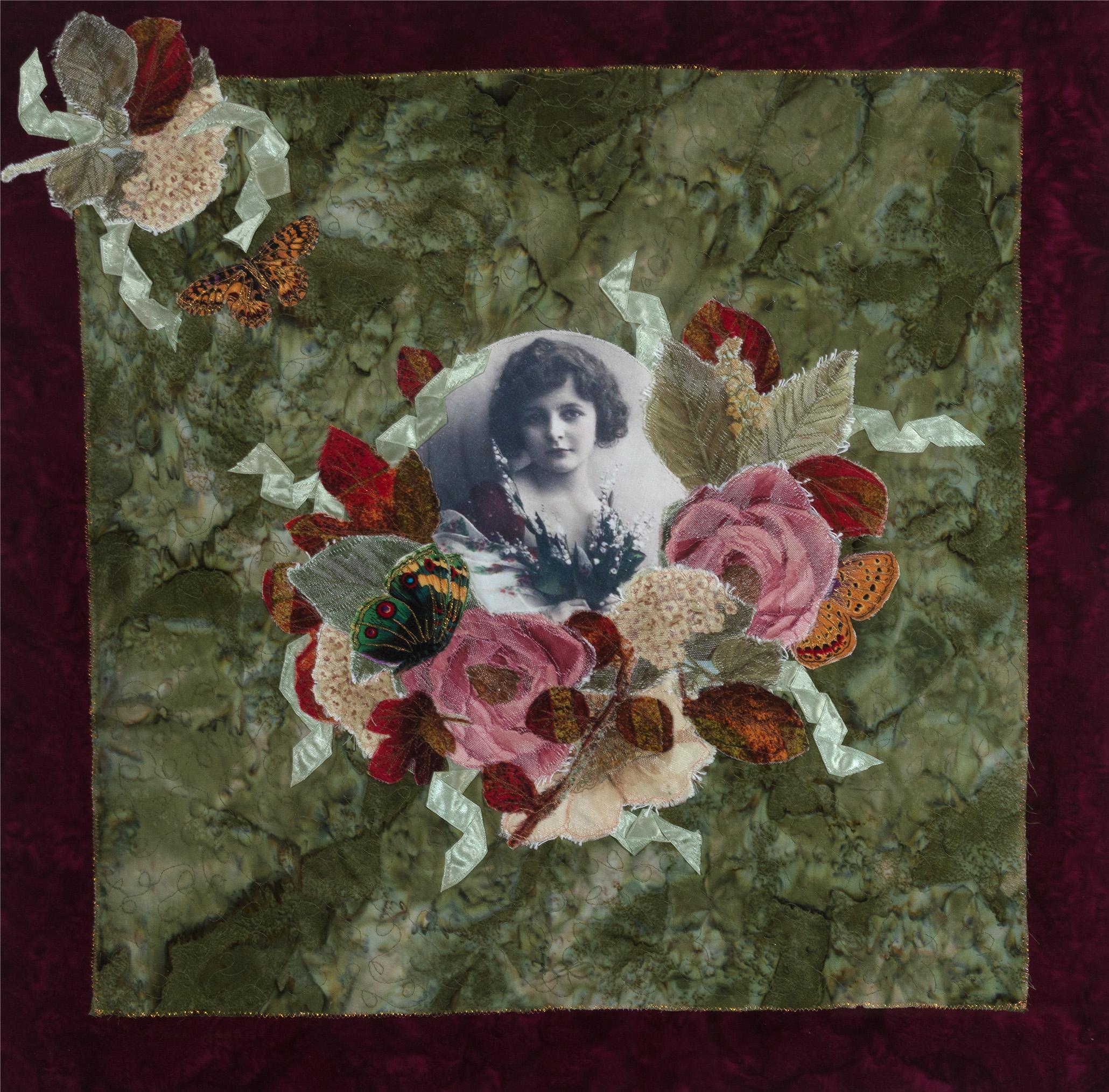 A floral arrangement made of a variety of textiles, surrounding a portrait in the center. Portrait is of a woman in a black and white vignette. Quilted together with a golden and glittery thread. Artist signed this piece in the lower left.