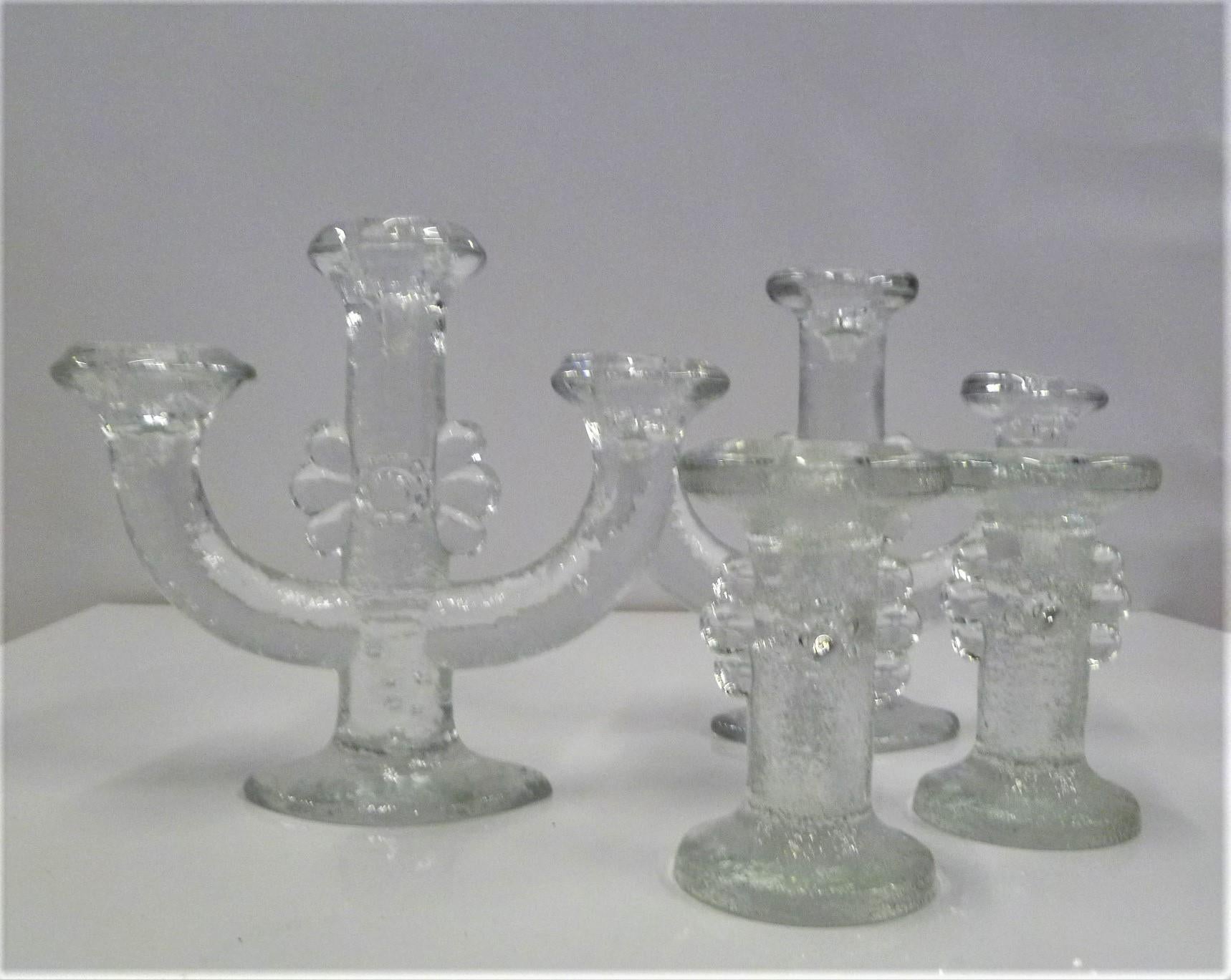 A grouping of 4 textured lead crystal glass candleholders from the 1970s by Swedish Designer Staffan Gellerstedt ( b. 1944) for Pukeberg Glassworks of Sweden. The set consists of heavily textured glass holders with an abstract flower motif, two