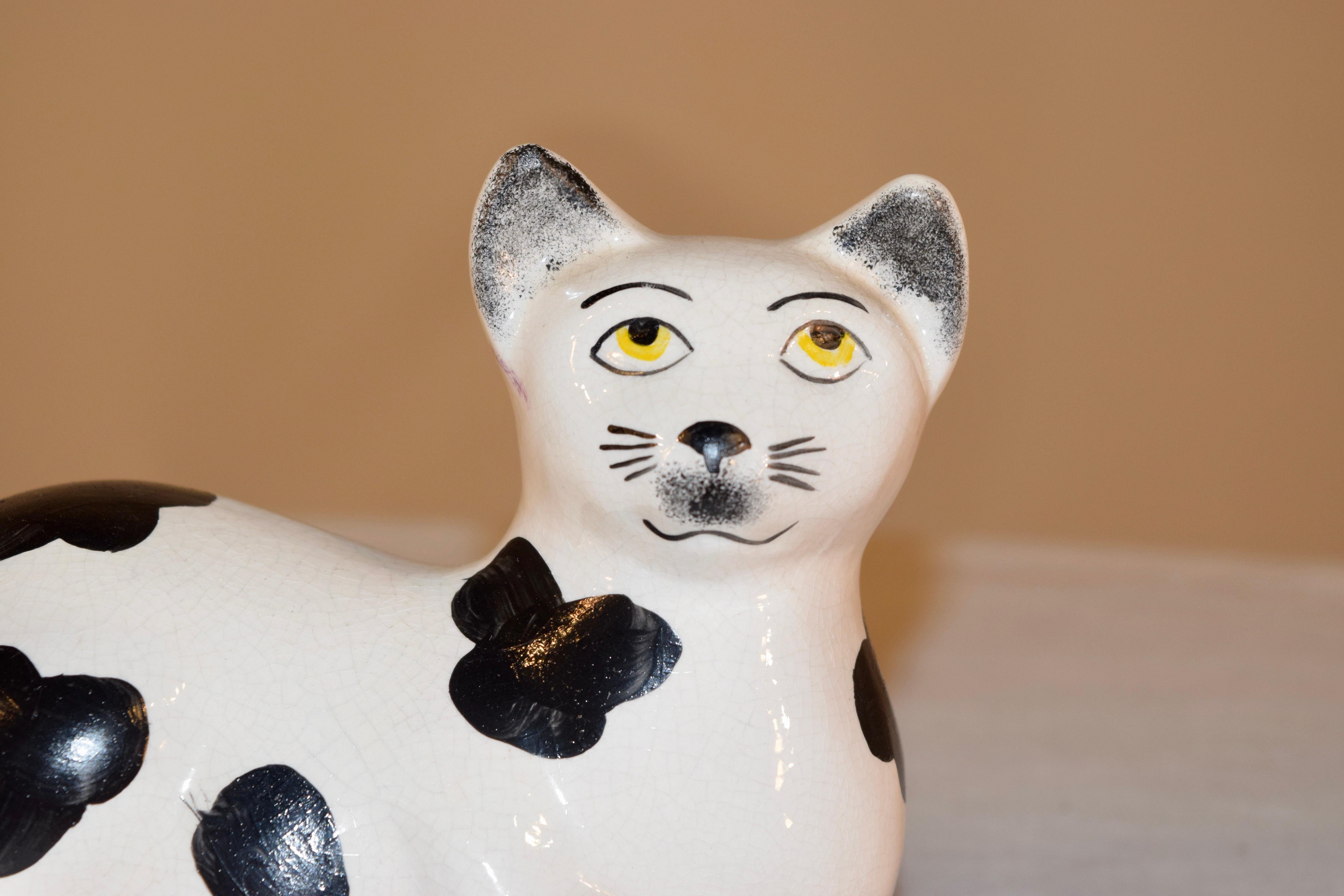Staffordshire cat figure made in England, circa 1970. The cat is in a lying position and is resting on a blue base.