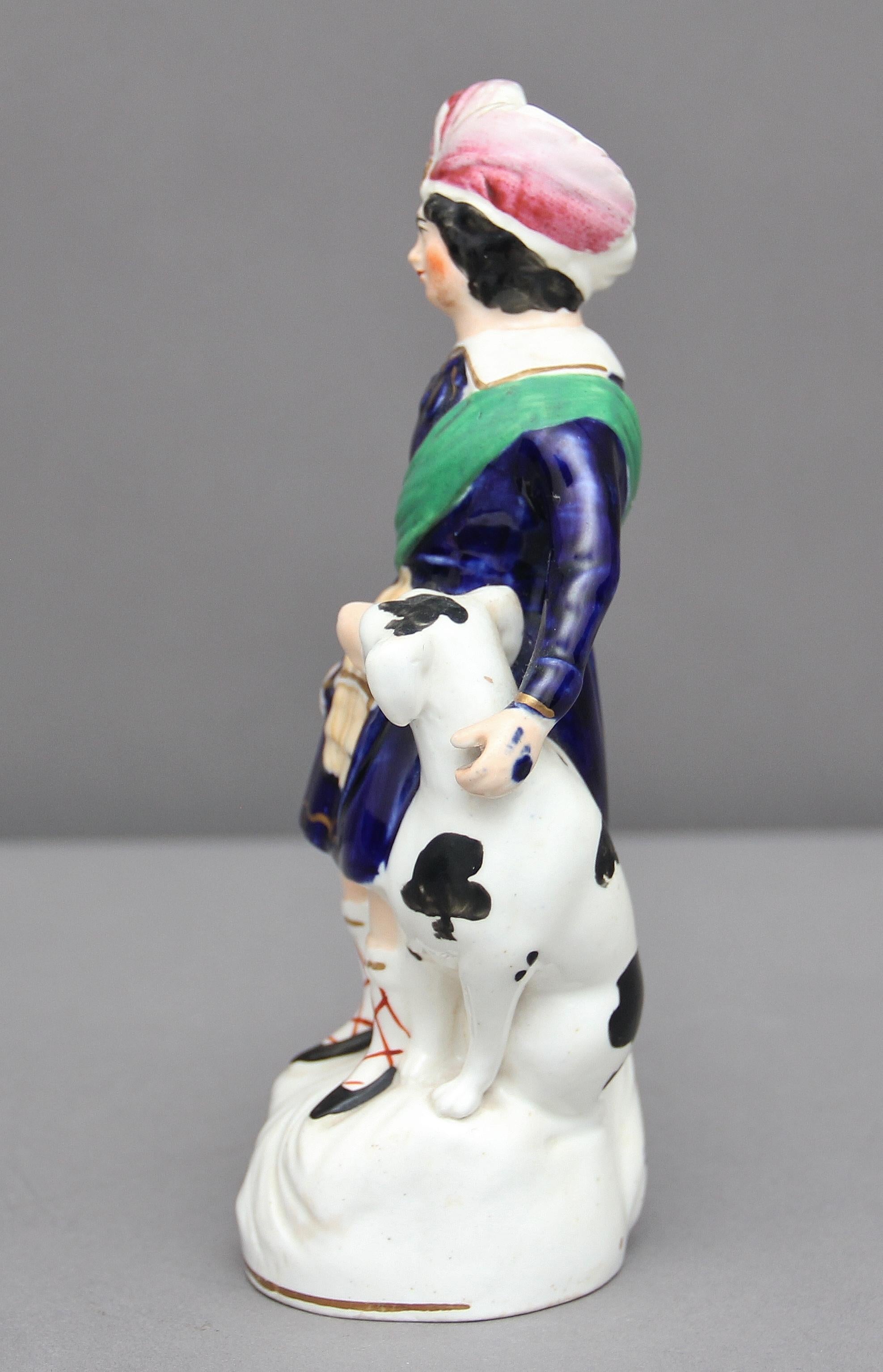 19th century Staffordshire figure of a young boy with a dog holding a whip and wearing a plumed hat, good color and in good condition, circa 1850.
 