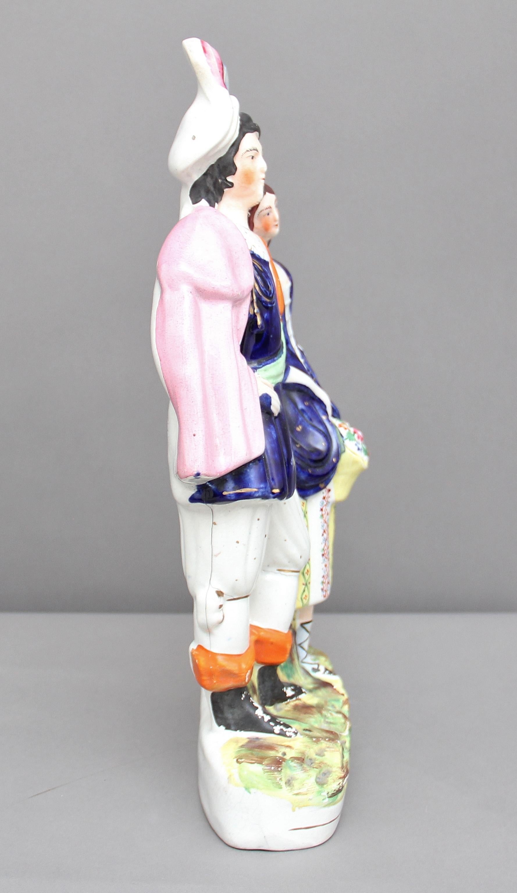 19th century Staffordshire figure of a man and woman, the woman holding a basket of flowers, good colors but sadly some cracks, circa 1850.