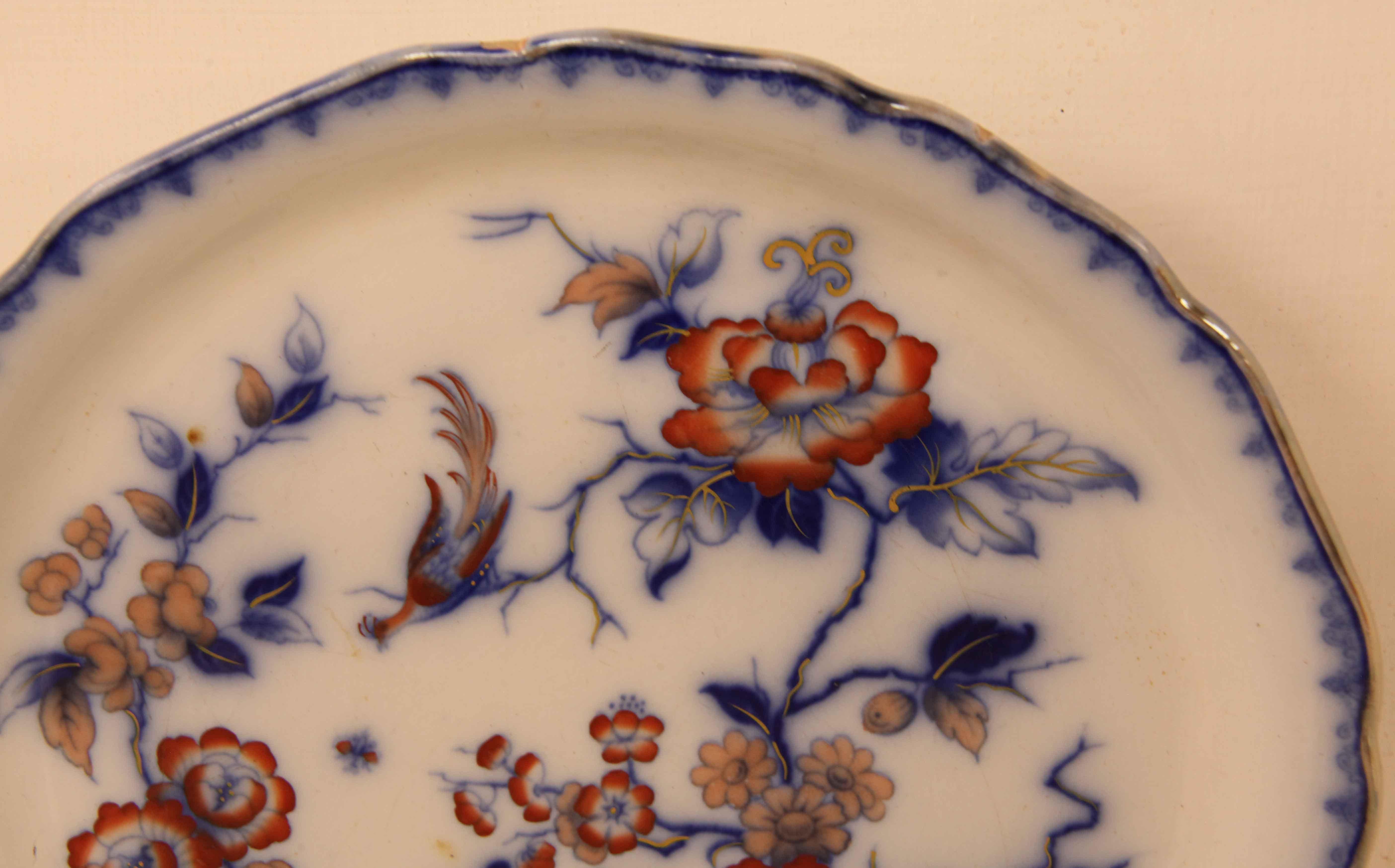 Staffordshire flow blue serving plate, the raised rim is decorated with a simple flow blue pattern , the main body with coral colored flowers and flow blue foliage, the under rim is also painted with flowers and foliage , the ''foot'' has a